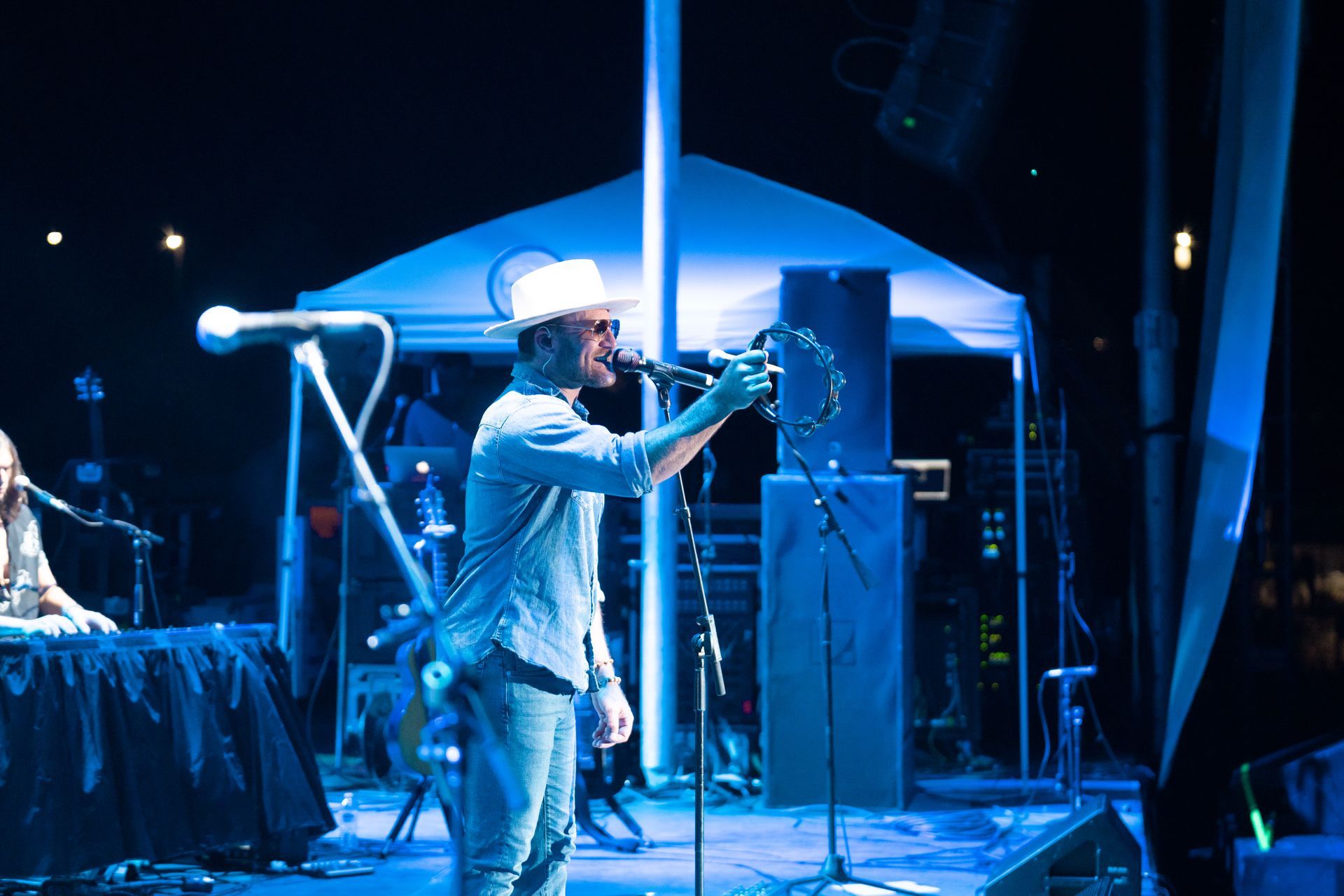 A man in a cowboy hat is singing into a microphone on a stage