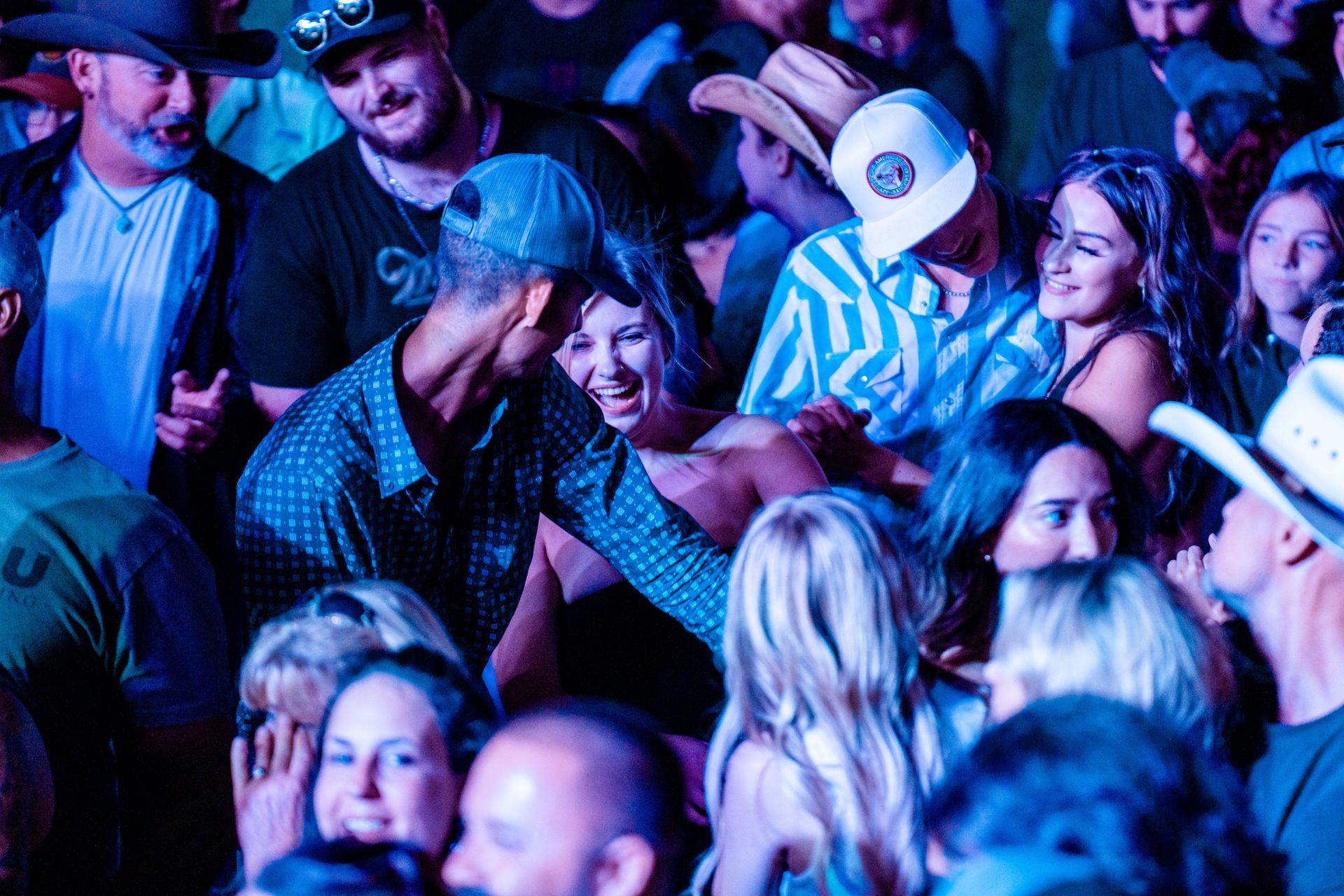A crowd of people are dancing in a dark room at a concert.