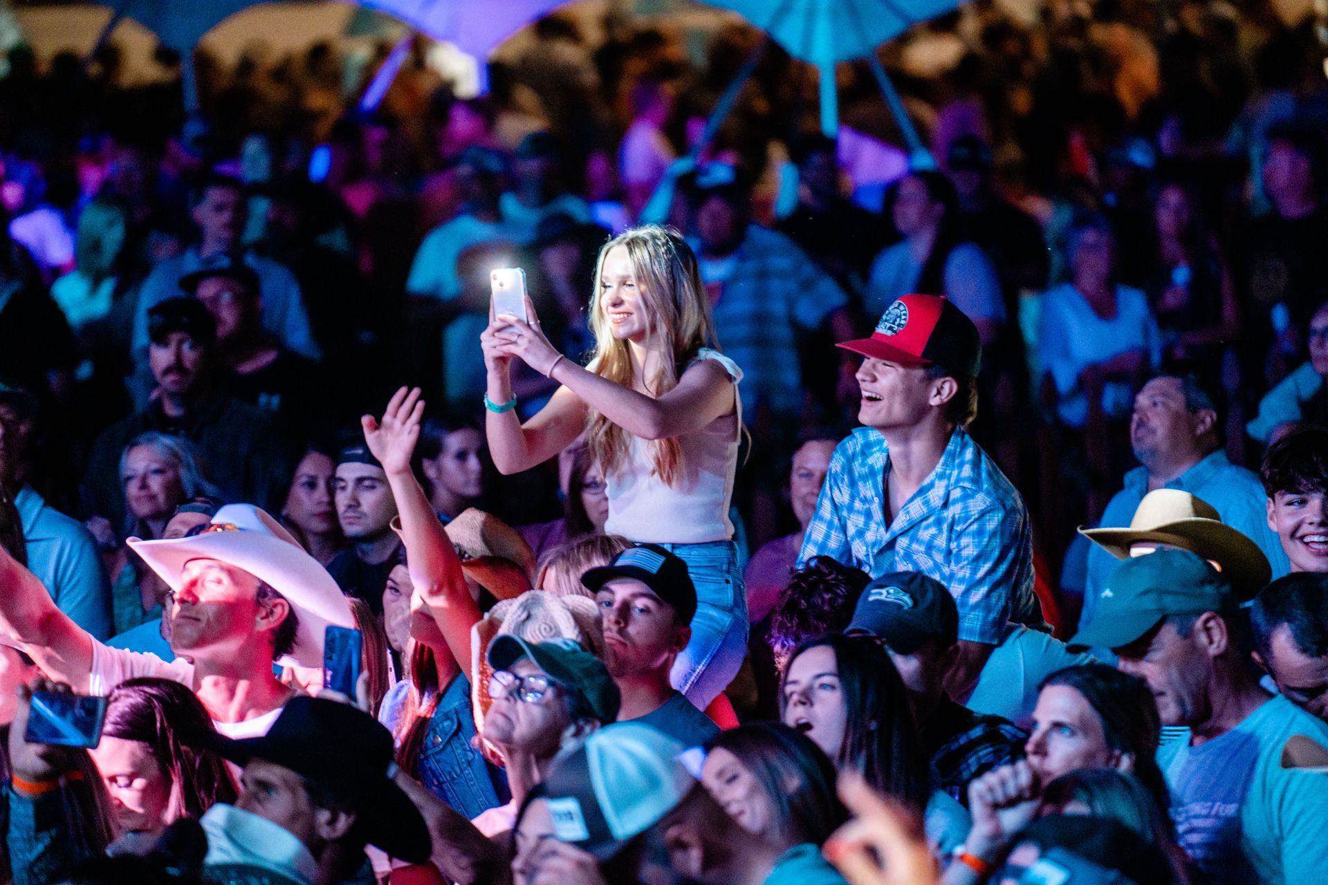 A woman is taking a picture of a crowd of people at a concert.