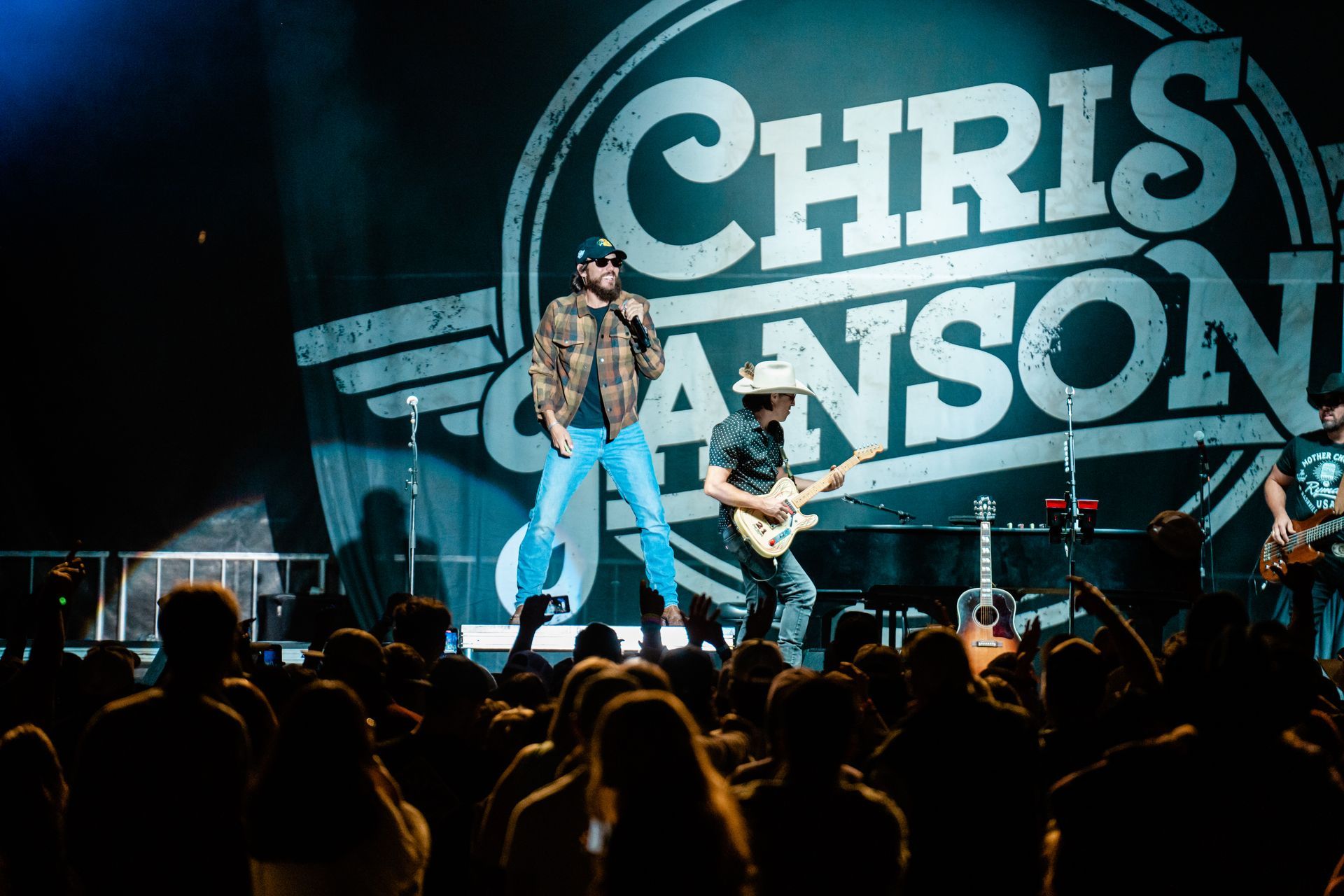 A man is singing into a microphone on a stage in front of a crowd.