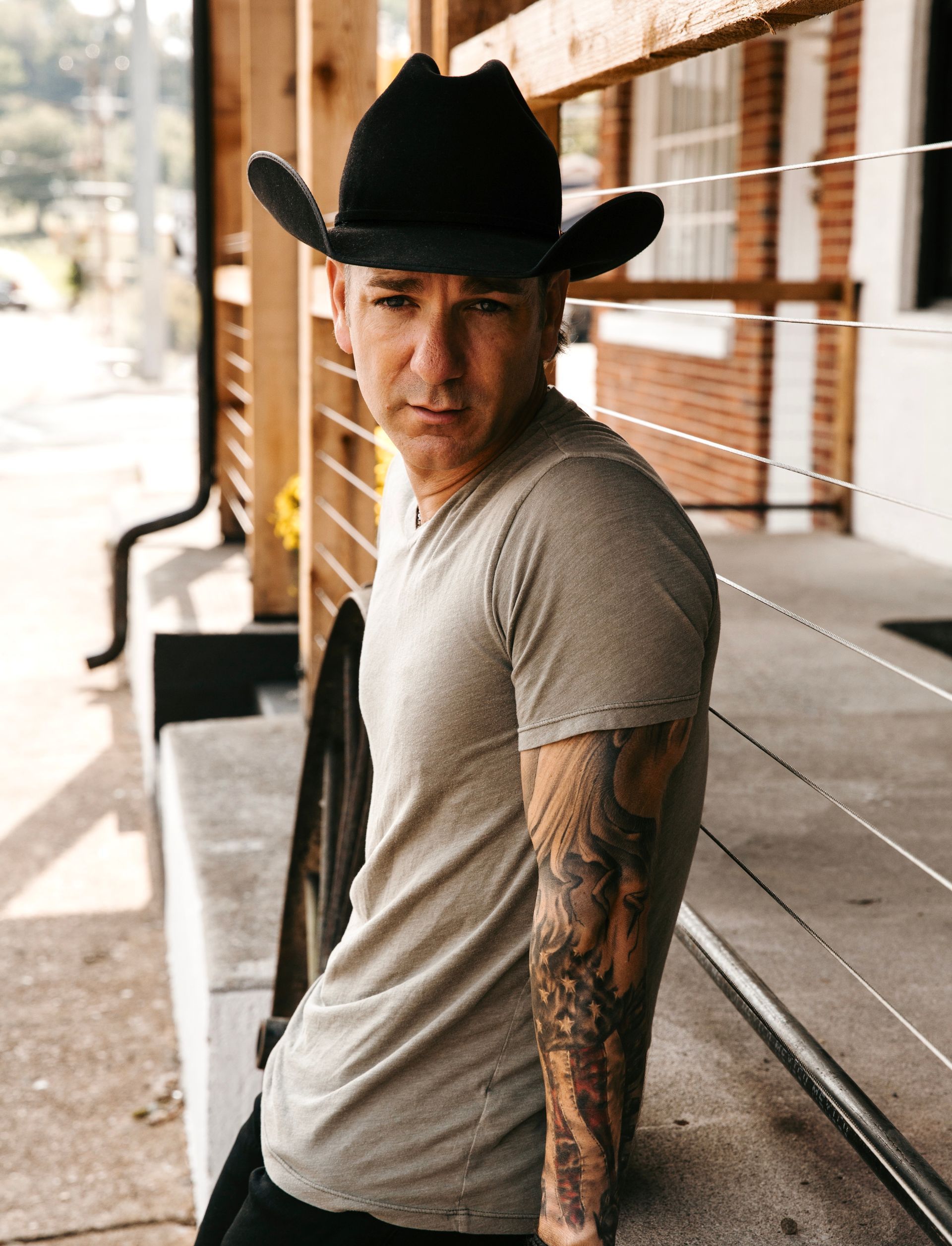 A man with a tattoo on his arm is wearing a cowboy hat.