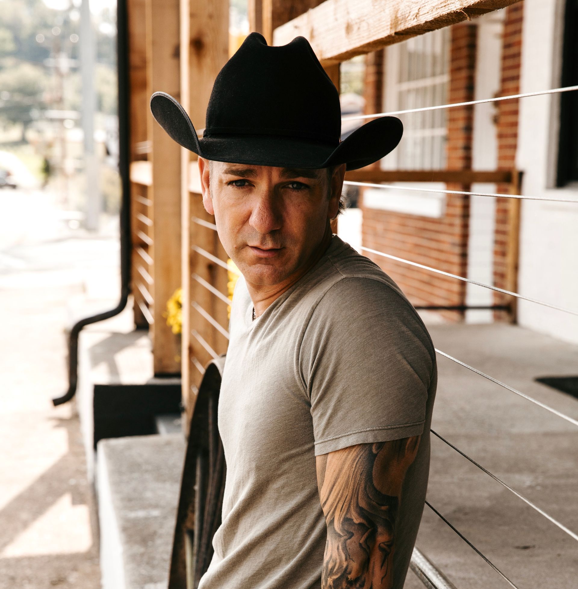 A man with a tattoo on his arm is wearing a cowboy hat.