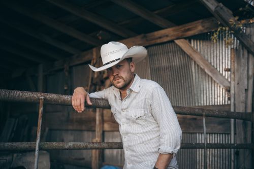 A man with a beard is standing in a field of tall grass.