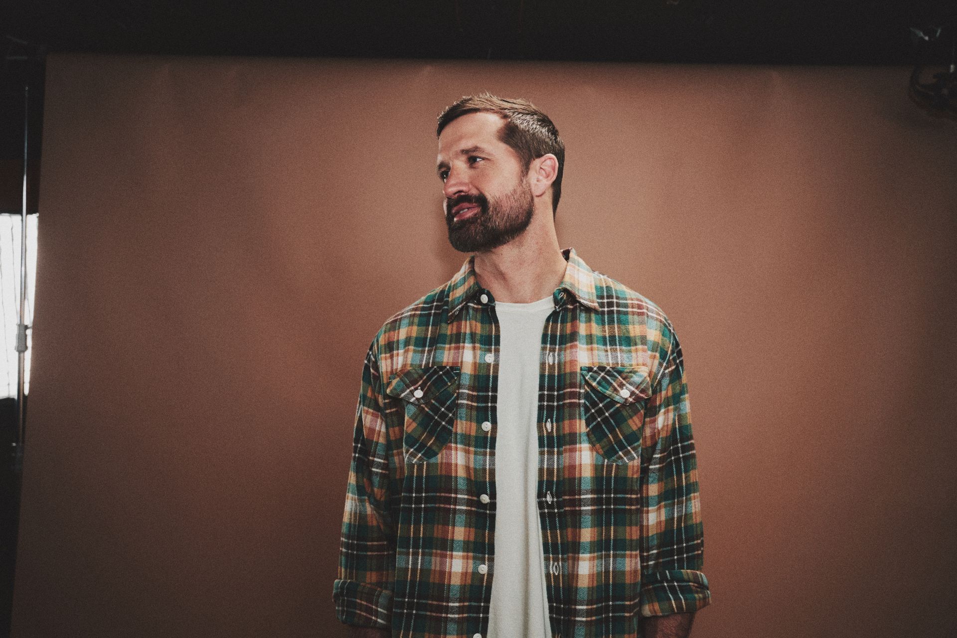 A man with a beard is standing in a field of tall grass.