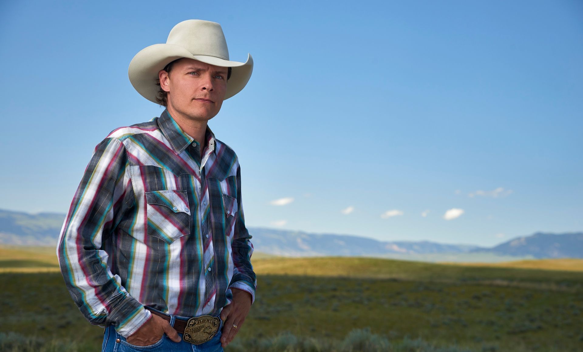 A man with a tattoo on his arm is wearing a cowboy hat.