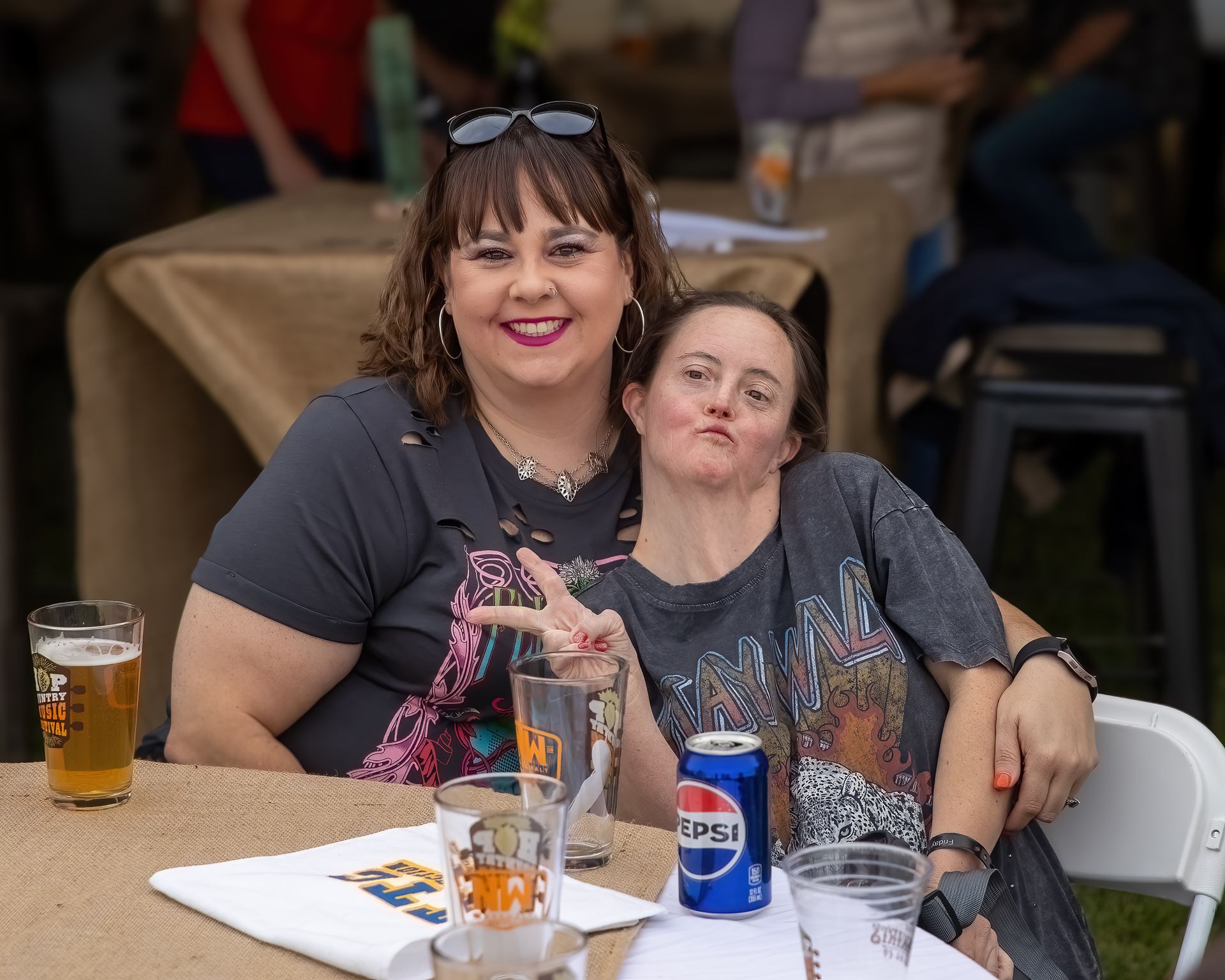 Two women are sitting at a table with a can of pepsi on it.