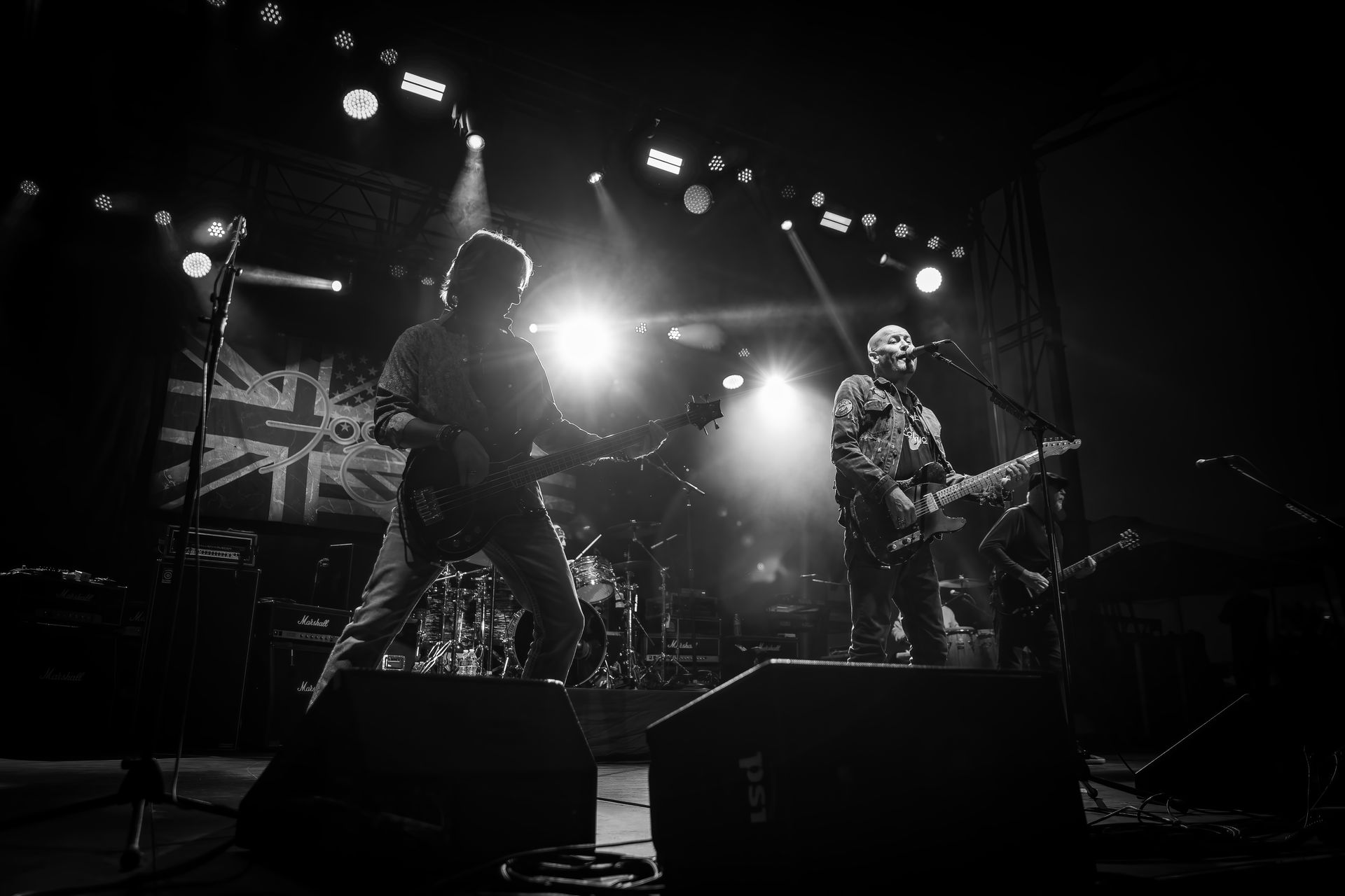 A black and white photo of two men playing guitars on a stage.