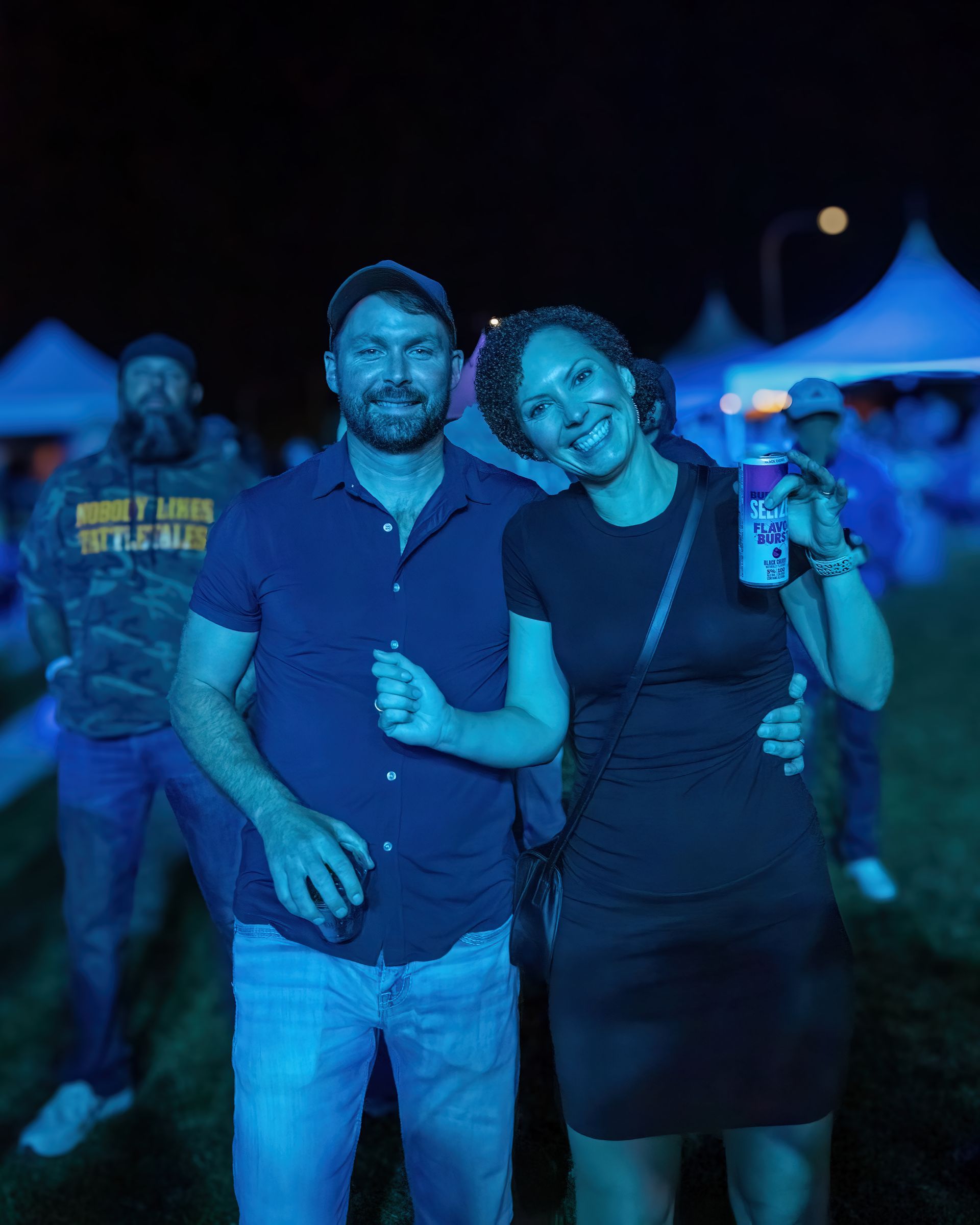 A man and a woman are posing for a picture at a concert.