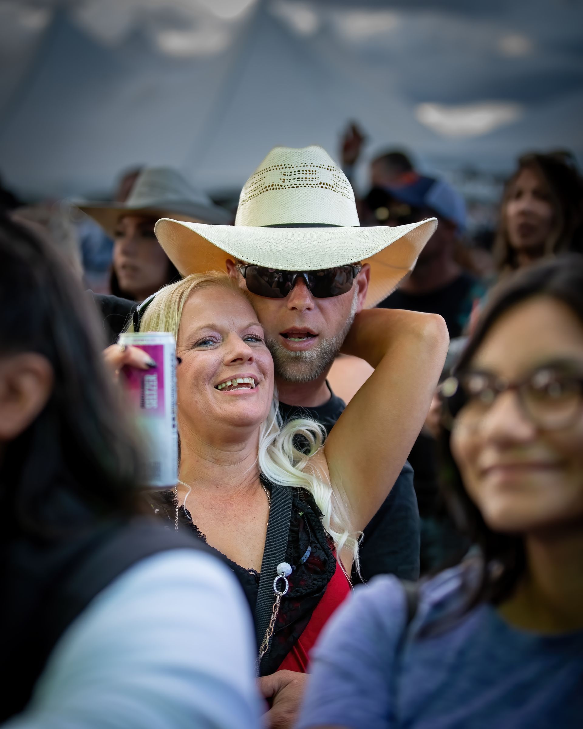A man wearing a cowboy hat is hugging a woman