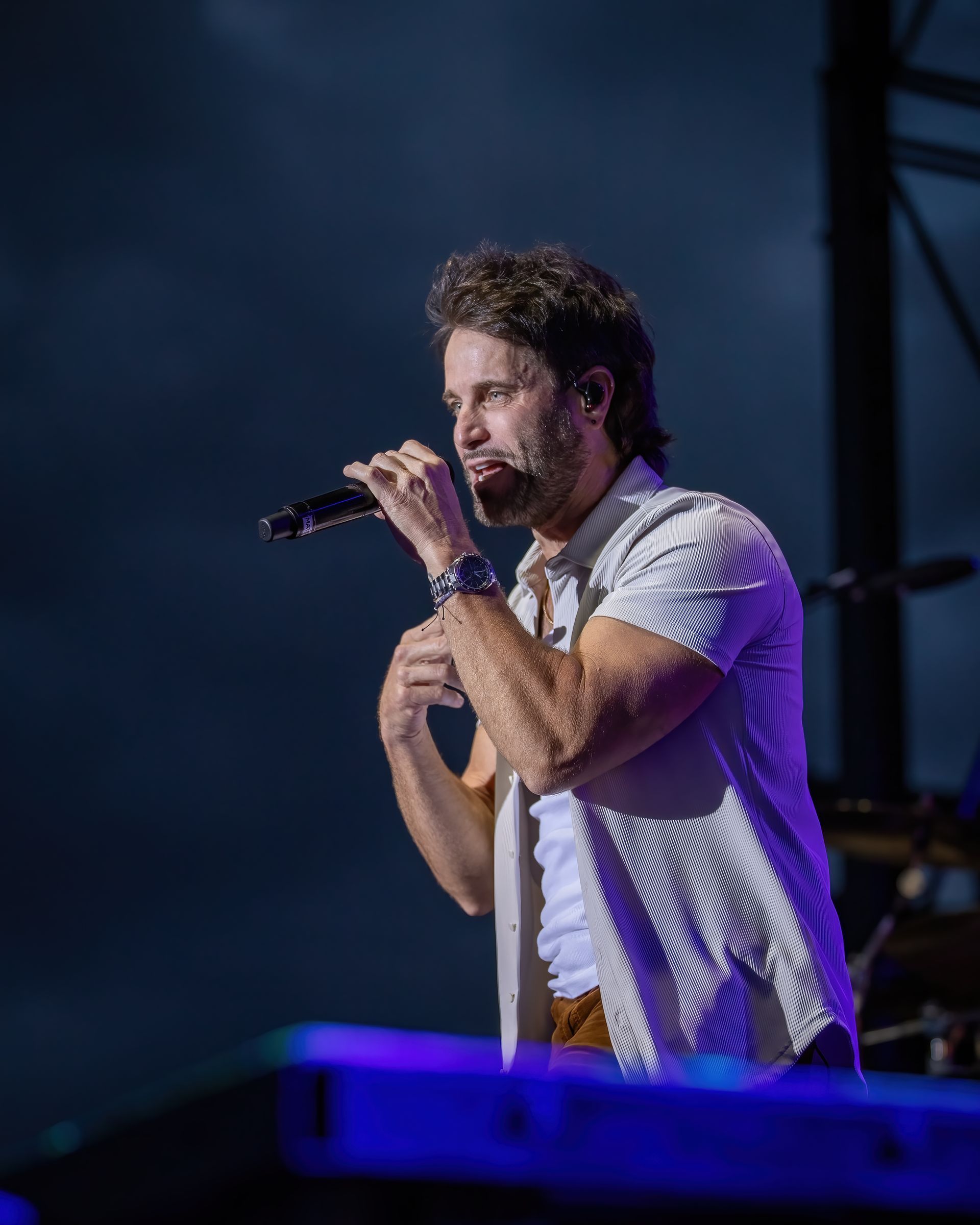 A man is singing into a microphone on a stage.