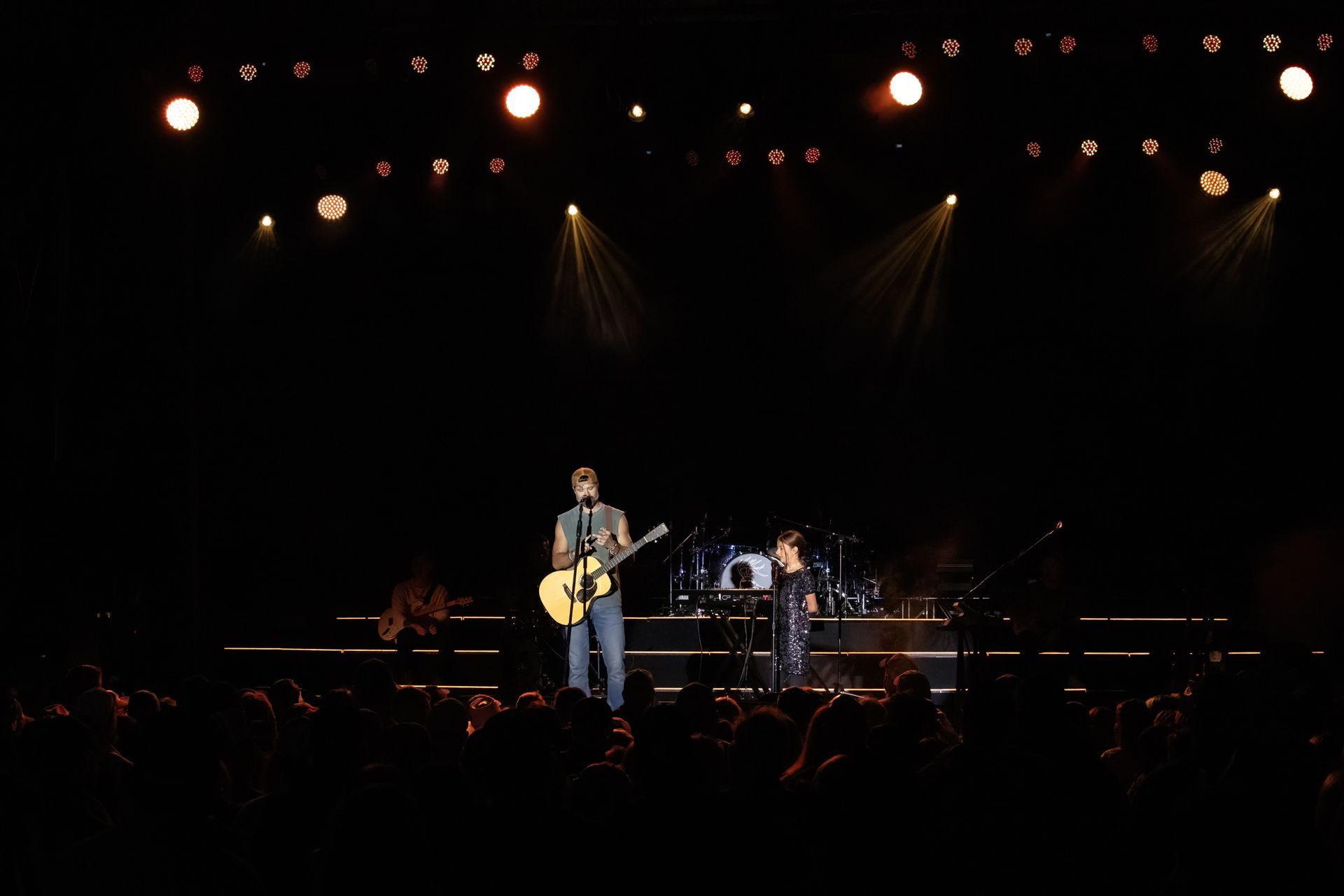 A man is playing a guitar on a stage in front of a crowd.