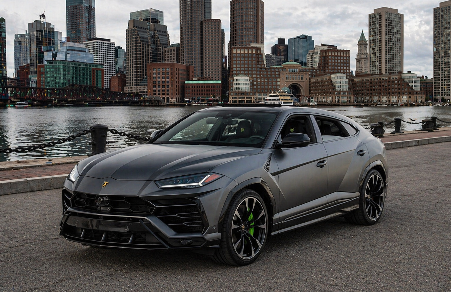 Gray Lamborghini Urus SUV on a road, dark wheels, bright sky.