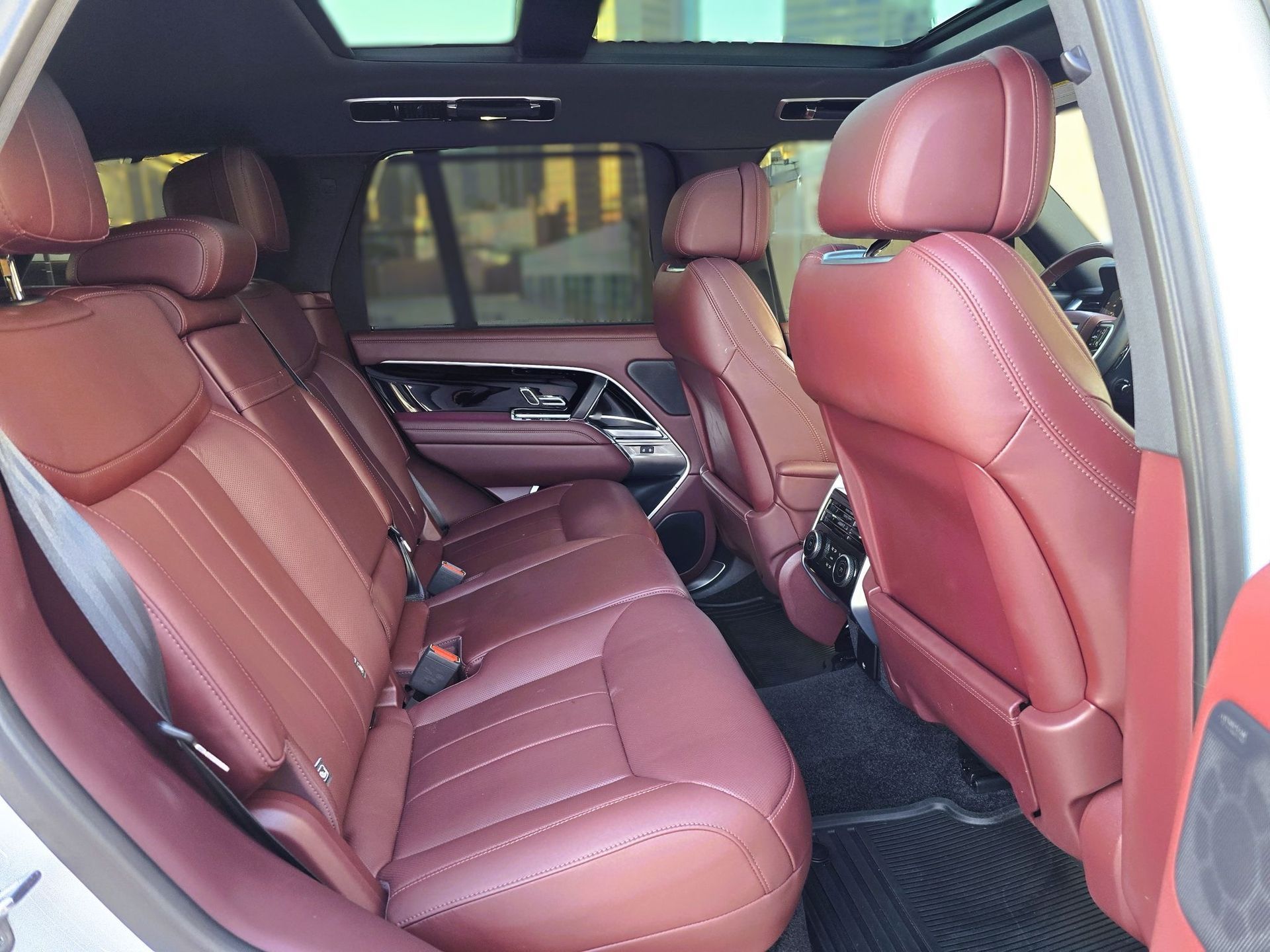 Red leather interior of a luxury SUV; rear seats, panoramic roof.