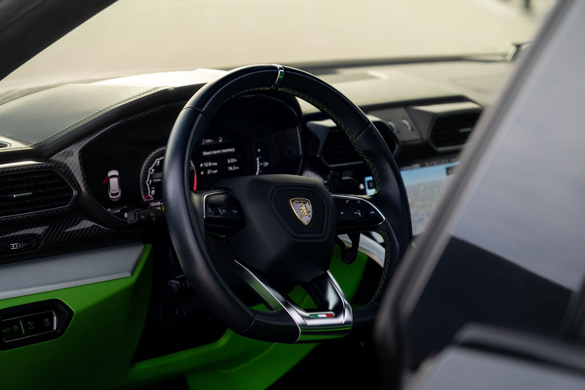 Black steering wheel with green and silver accents in a luxury car.