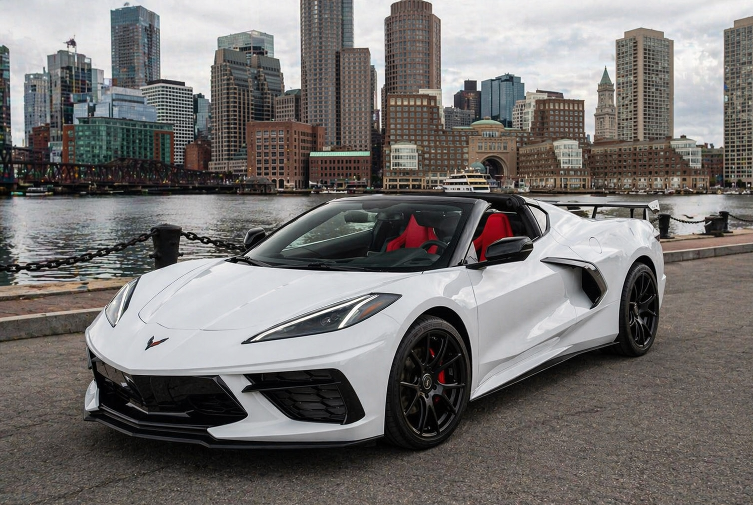 White Corvette convertible in a dark parking garage. Red interior, black wheels.
