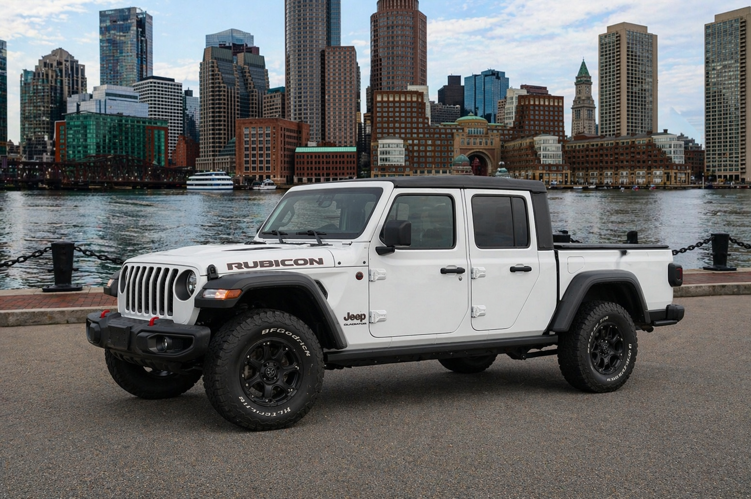 White Jeep Gladiator parked by the water with a city skyline in the background