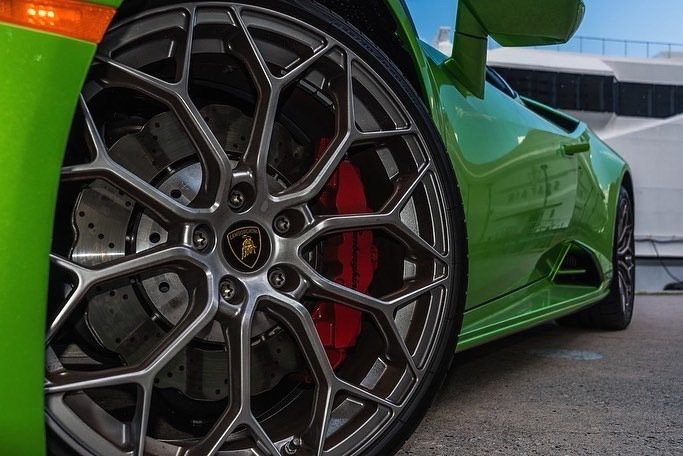 Green Lamborghini sports car with silver wheel and red brake calipers.