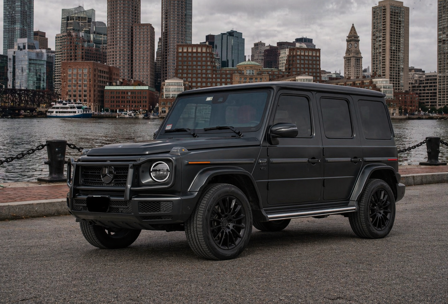 Black Mercedes-Benz G-Wagon SUV with black wheels and a silver side step.  Parked in a gray garage.