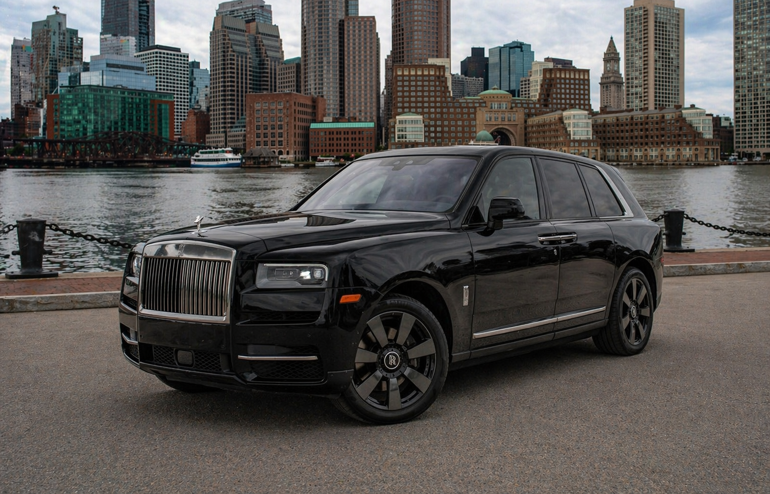 Black Rolls-Royce Cullinan SUV on a paved surface, set against a dusky sky.