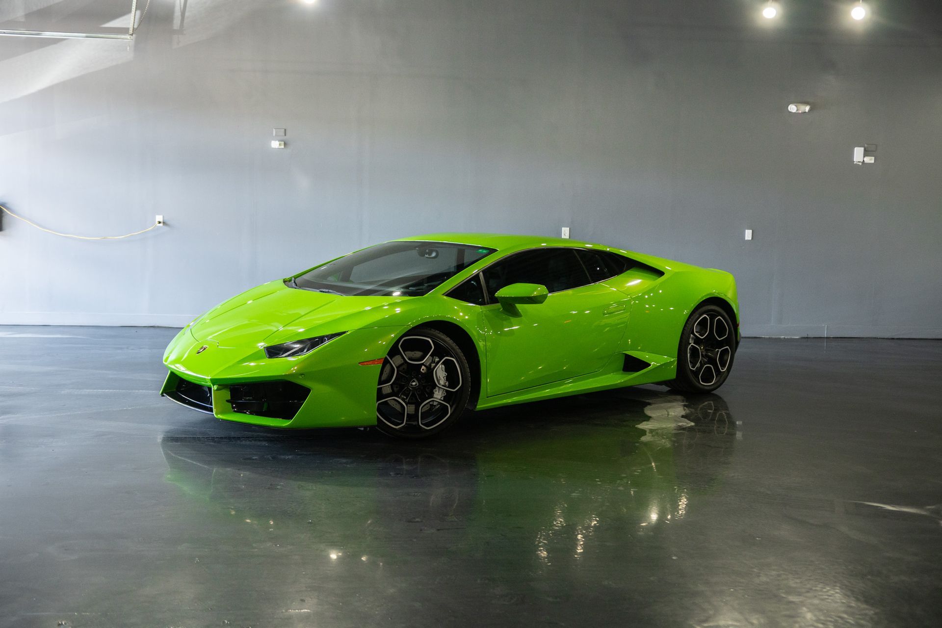 Green Lamborghini sports car in a showroom with a glossy floor.