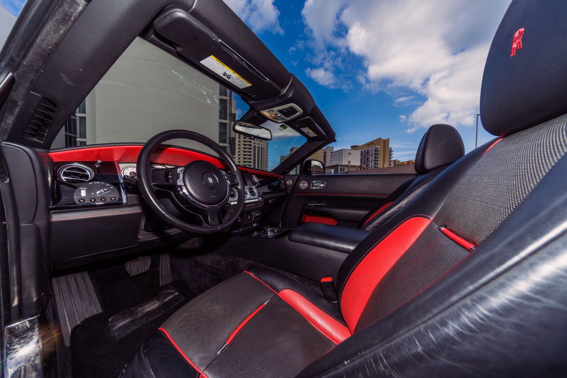 Interior of a black and red convertible car, sunny day.