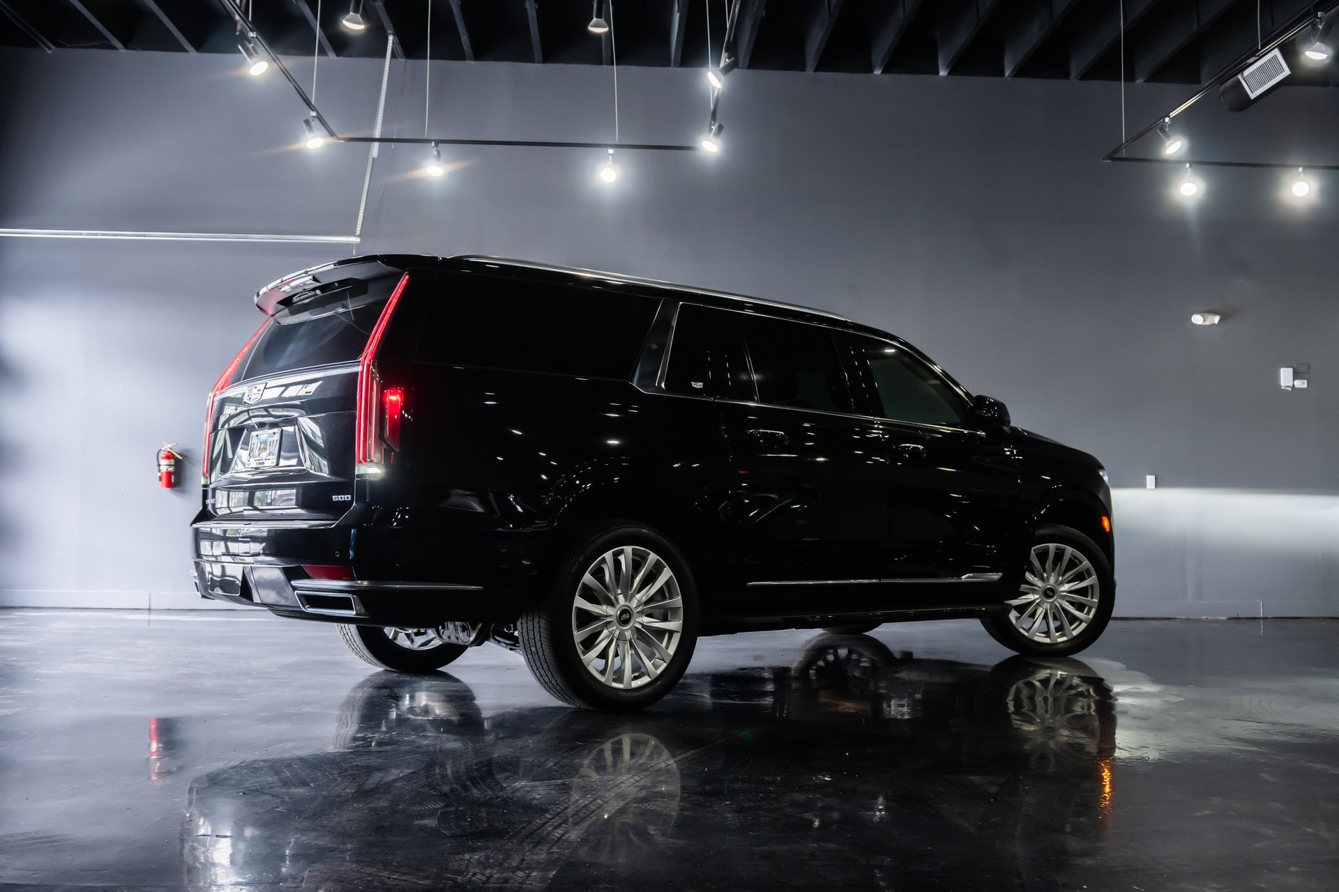 Black Cadillac Escalade SUV parked indoors with bright lights.