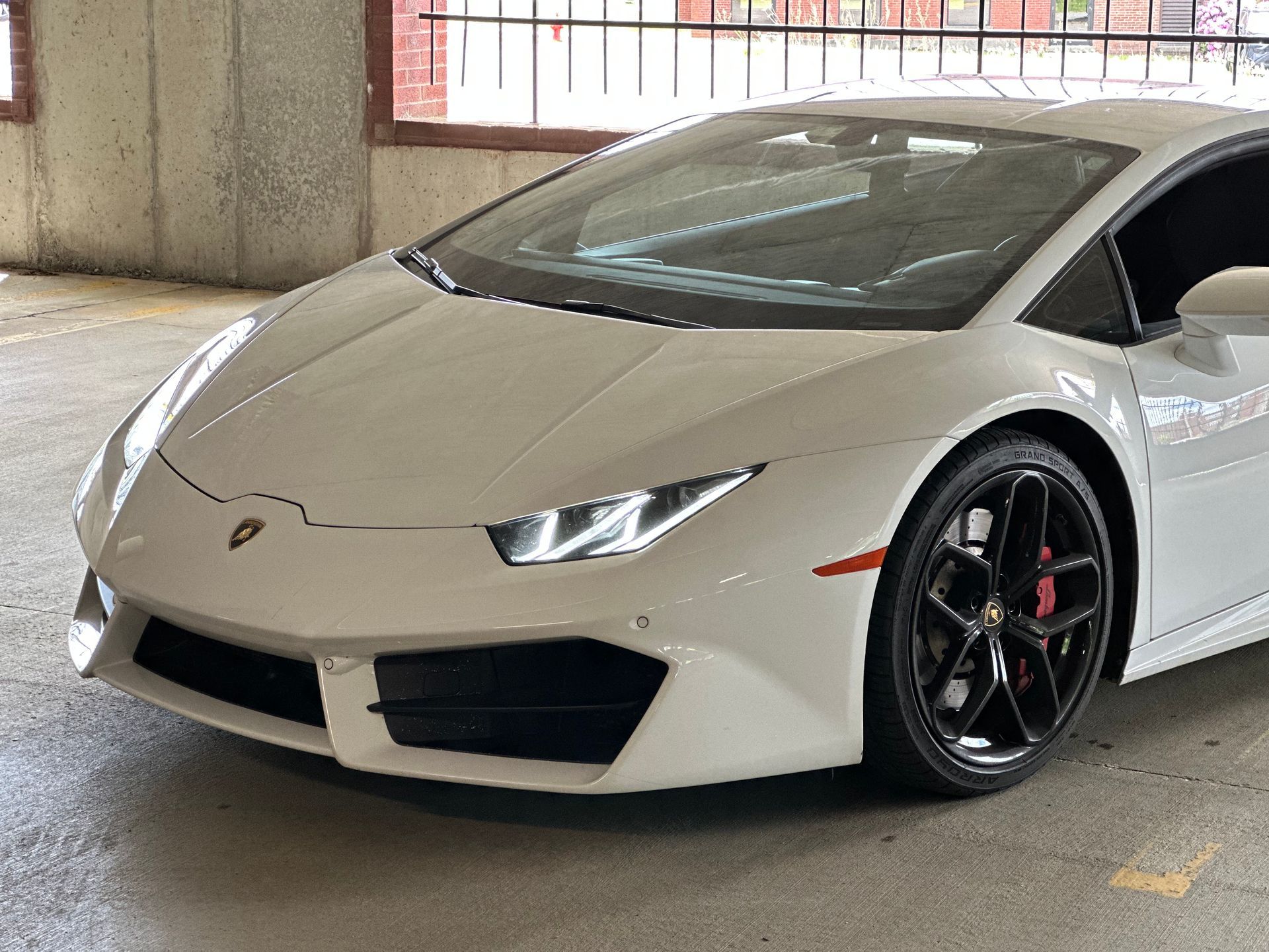 White Lamborghini sports car parked in a garage with black wheels and red brake calipers.