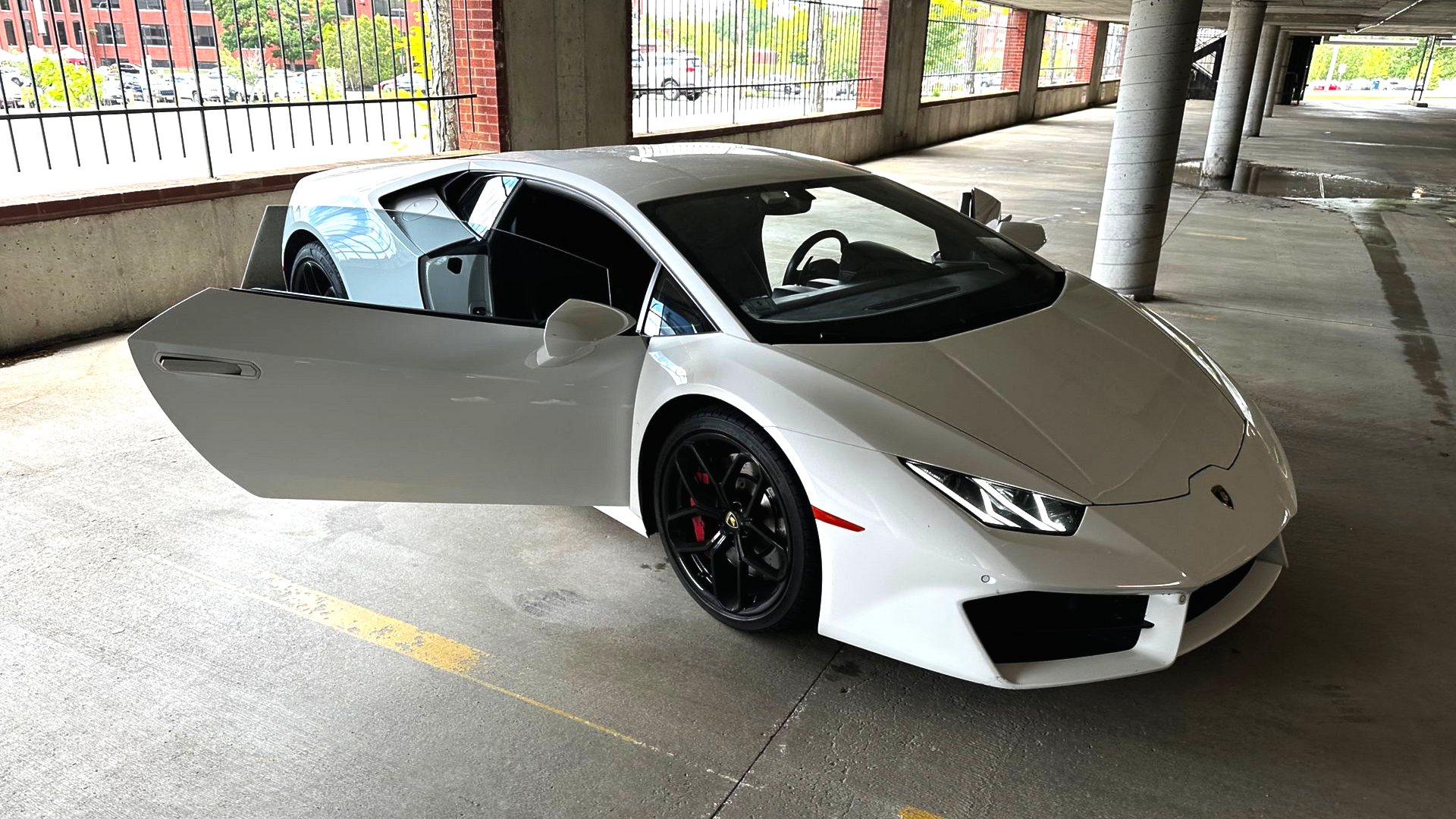 White Lamborghini with the door open parked in a parking garage.