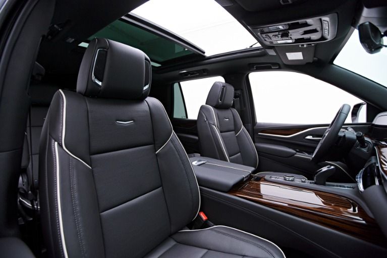 Black leather car interior with white stitching, panoramic sunroof, and wood trim.