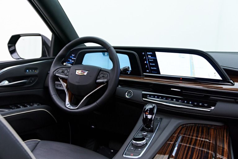 Cadillac Escalade interior: black dashboard with wood trim, steering wheel, and large display screen.