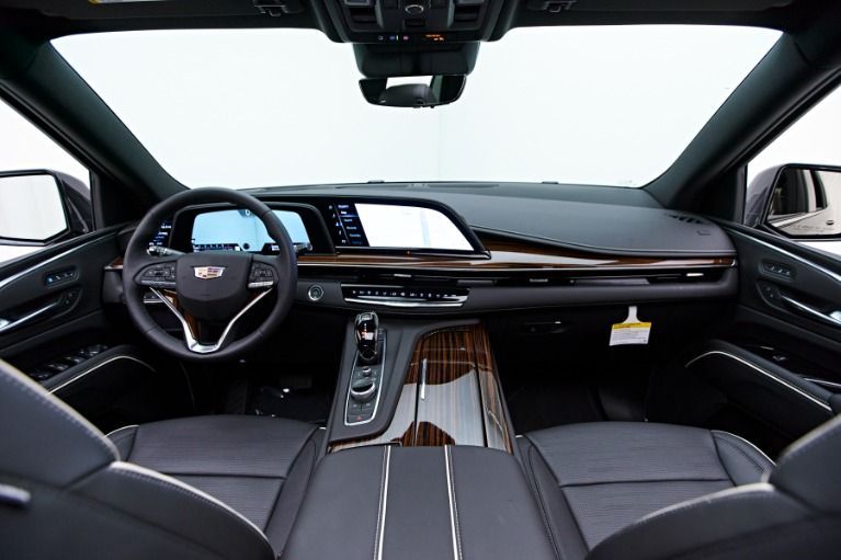 Interior view of a Cadillac car dashboard, with a steering wheel, displays, and wood trim accents.