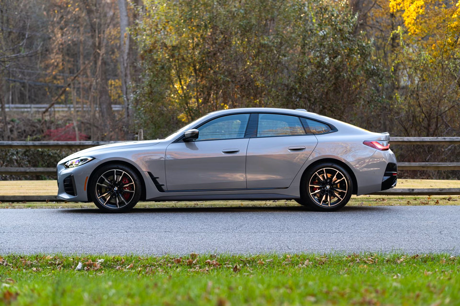 Gray BMW sedan parked on a road. Fall foliage in the background.