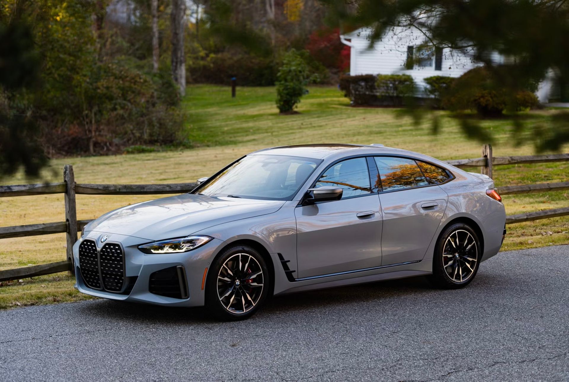 Gray BMW sedan parked on a driveway with a wooden fence and house in the background.
