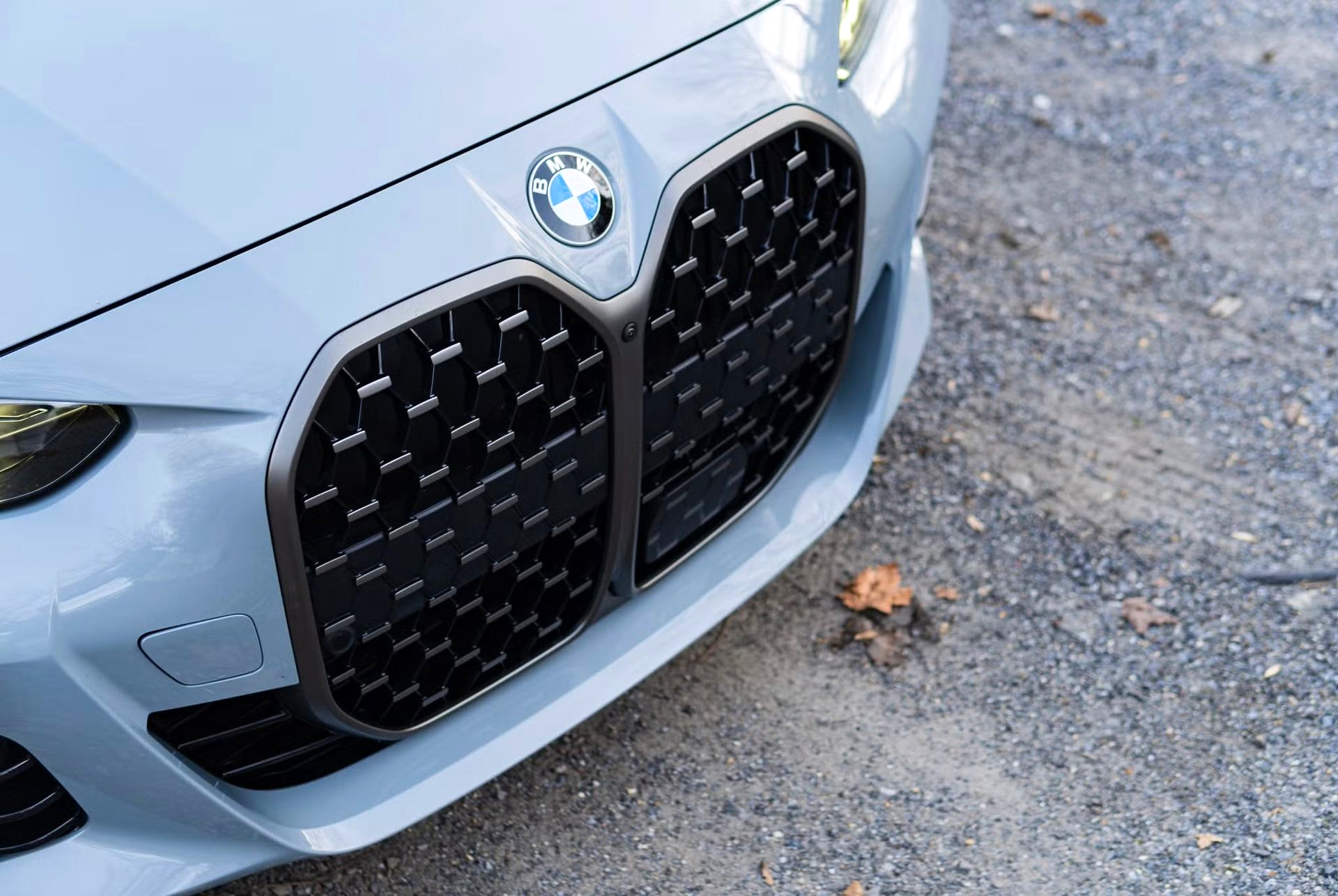 Close-up of a light gray BMW car's front with a large, black grille and BMW logo on the hood.