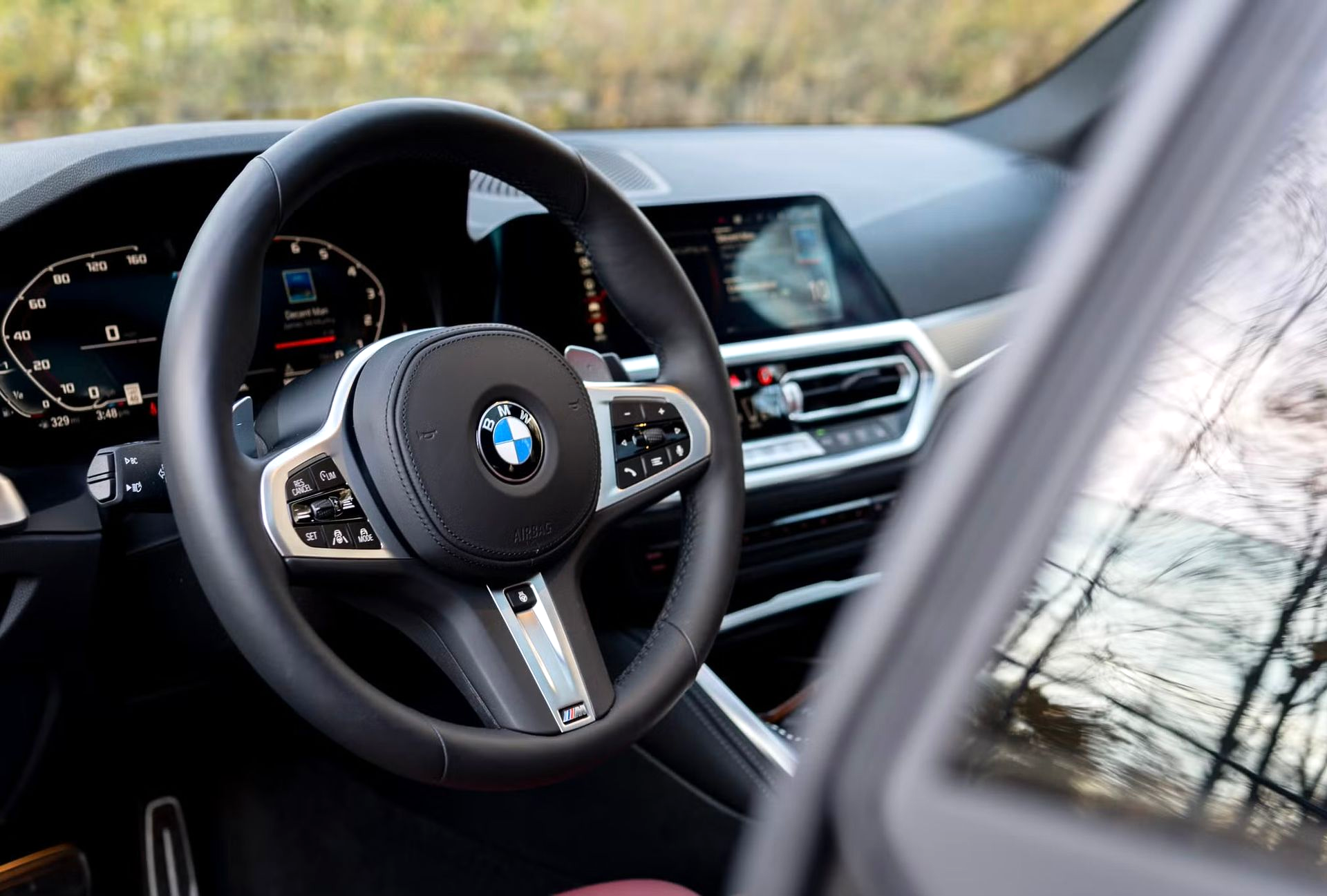 Interior of a BMW car: steering wheel, dashboard, and display screen.