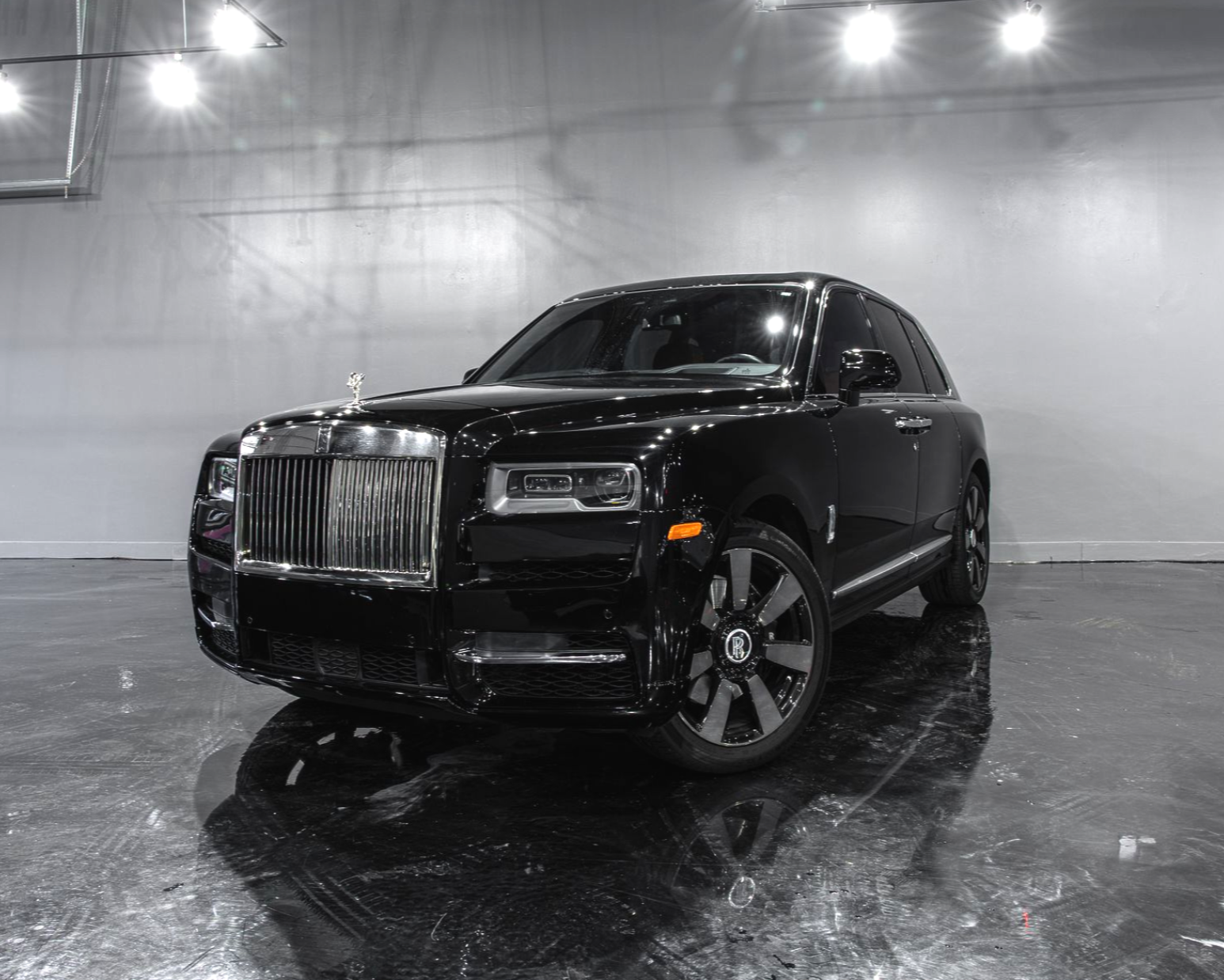 Black Rolls-Royce Cullinan SUV on a paved surface, set against a dusky sky.