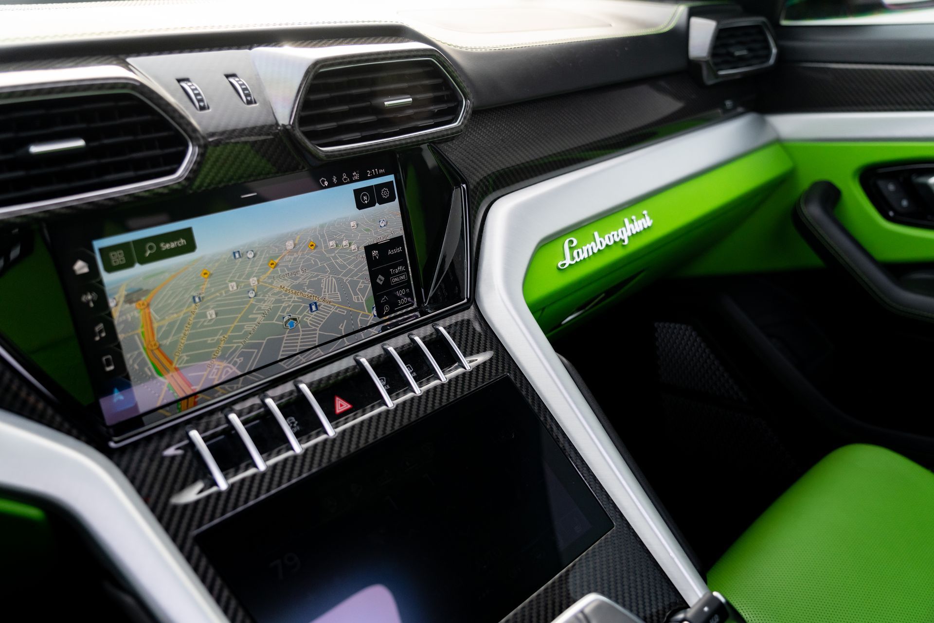 Lamborghini Urus interior dashboard: black, carbon fiber, silver, and lime green accents. Navigation displayed on touchscreen.