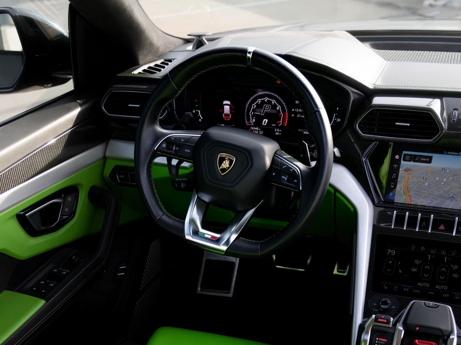 Interior view of a Lamborghini Urus, showing the steering wheel, dashboard, and green accents.