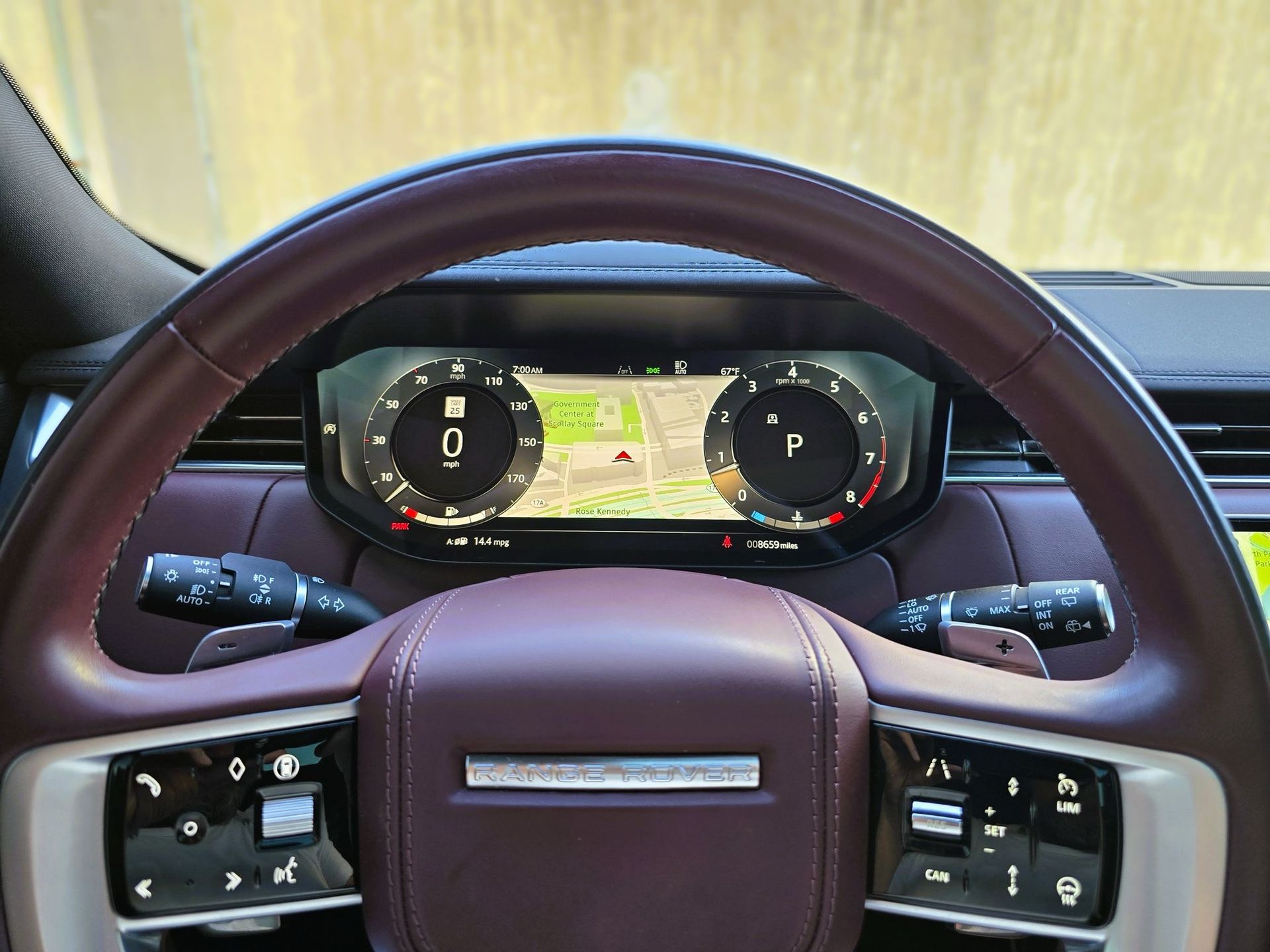 Burgundy steering wheel and dashboard of a car, displaying a navigation map and gauges.