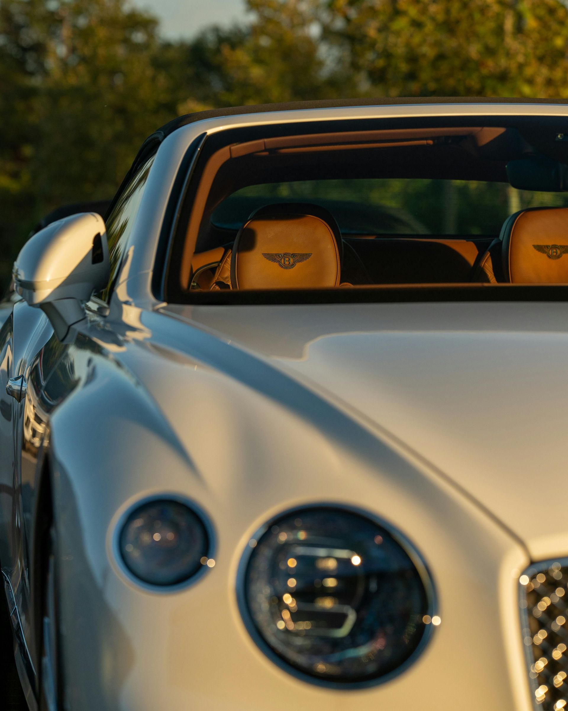 White Bentley convertible with tan interior, in an outdoor setting.