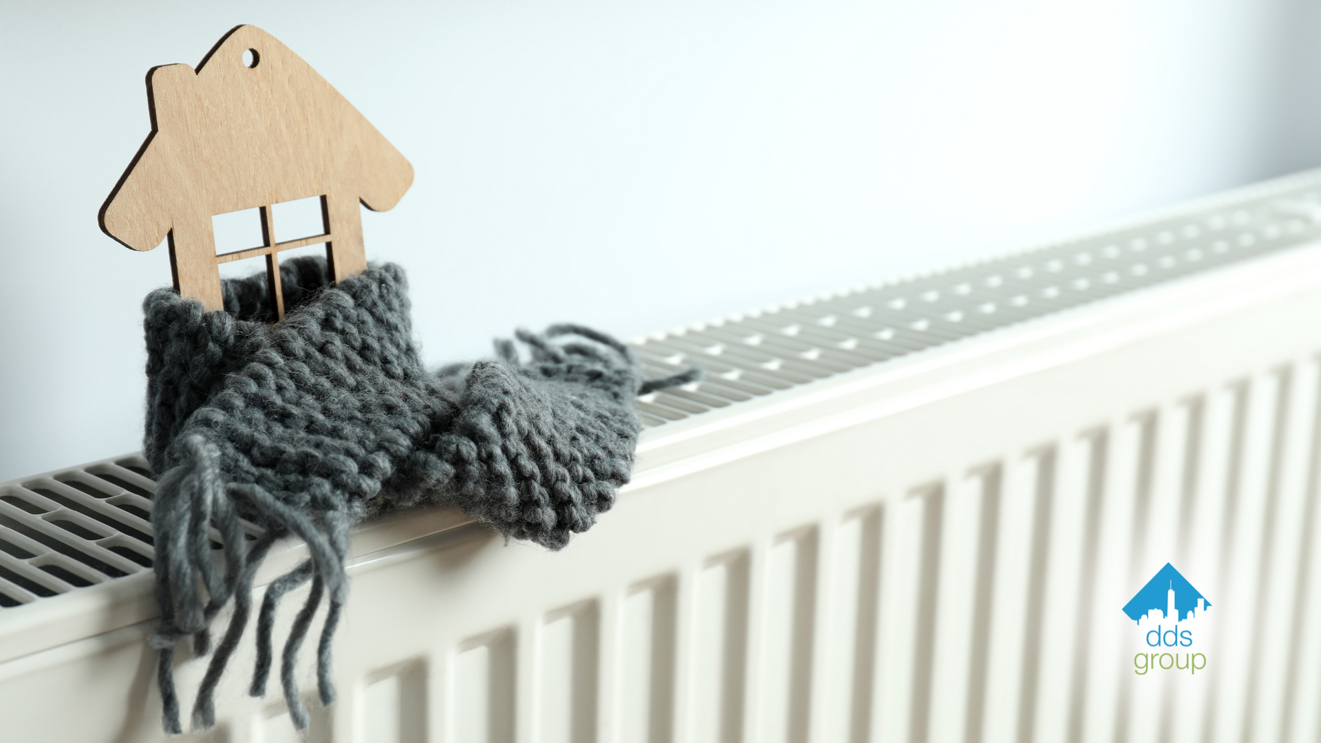 A wooden house is sitting on top of a radiator with a scarf around it.