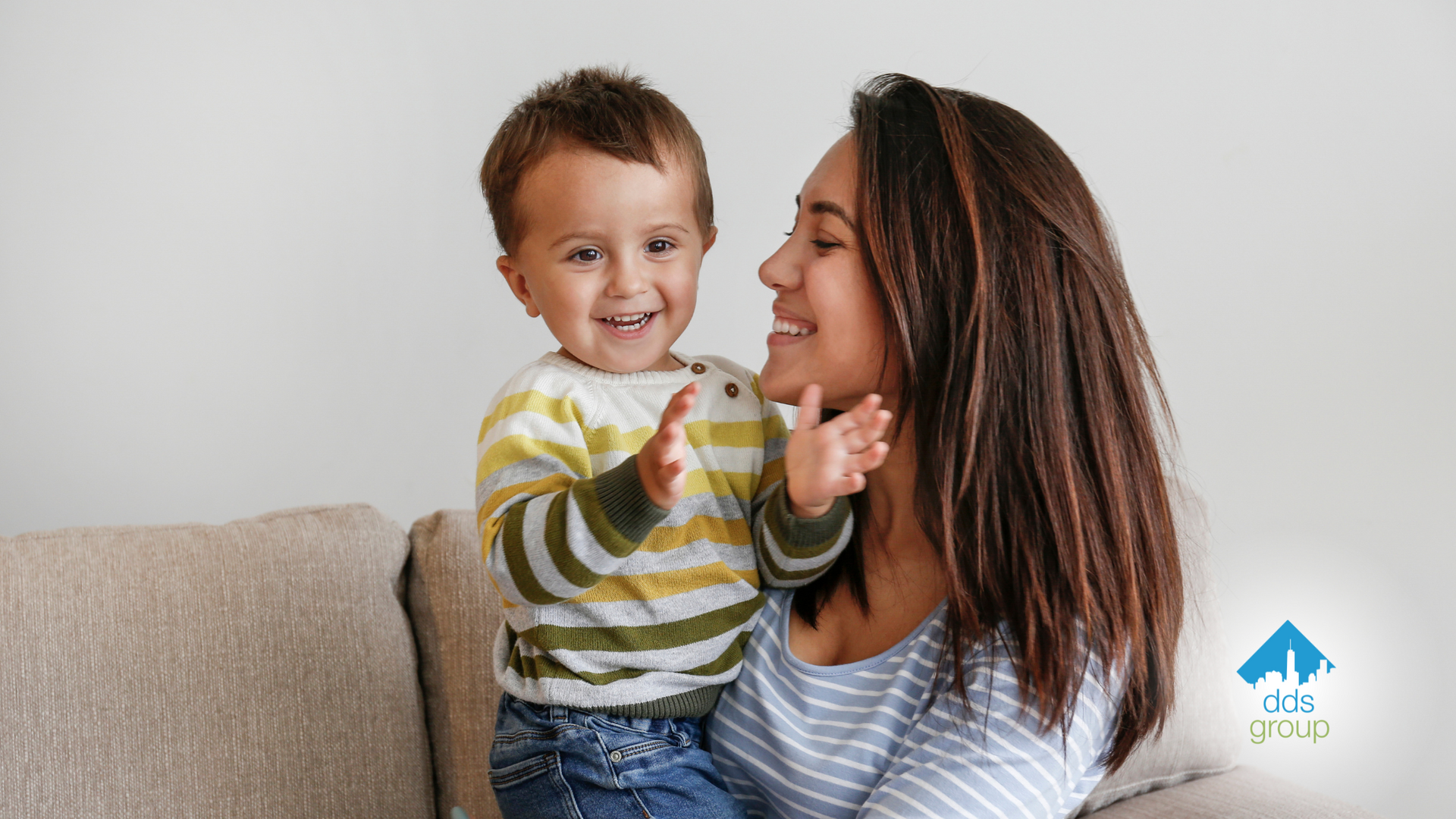 A woman is sitting on a couch holding a little boy in her arms.