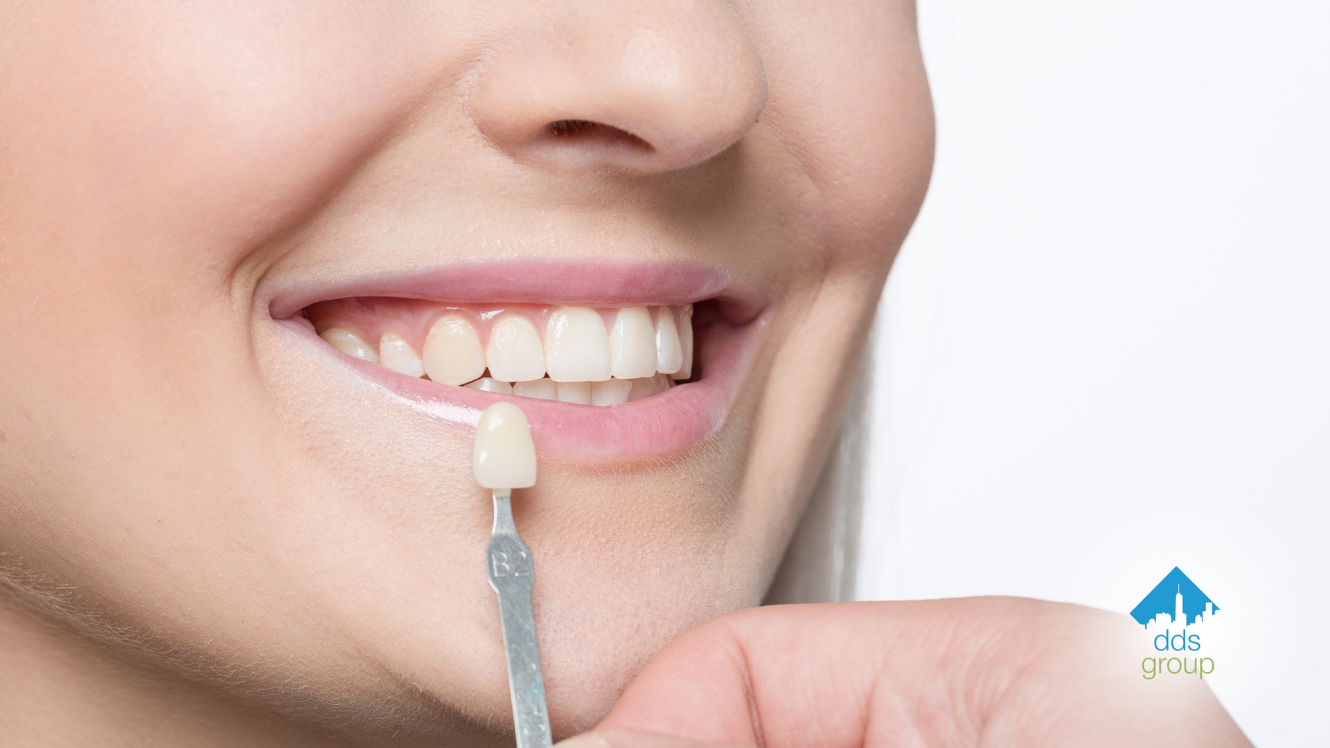 A woman is holding a sample of her teeth in front of her mouth.