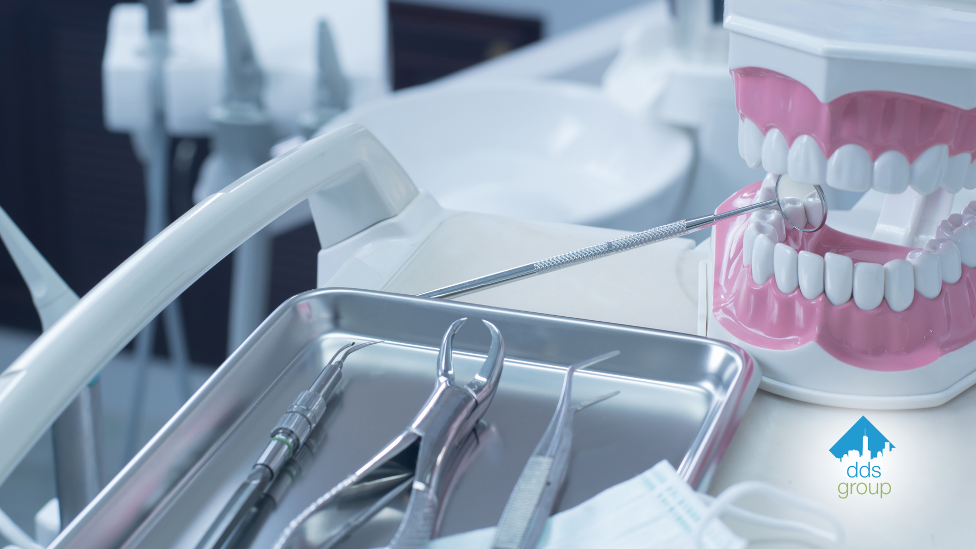 A tray of dental instruments and a model of teeth on a table.