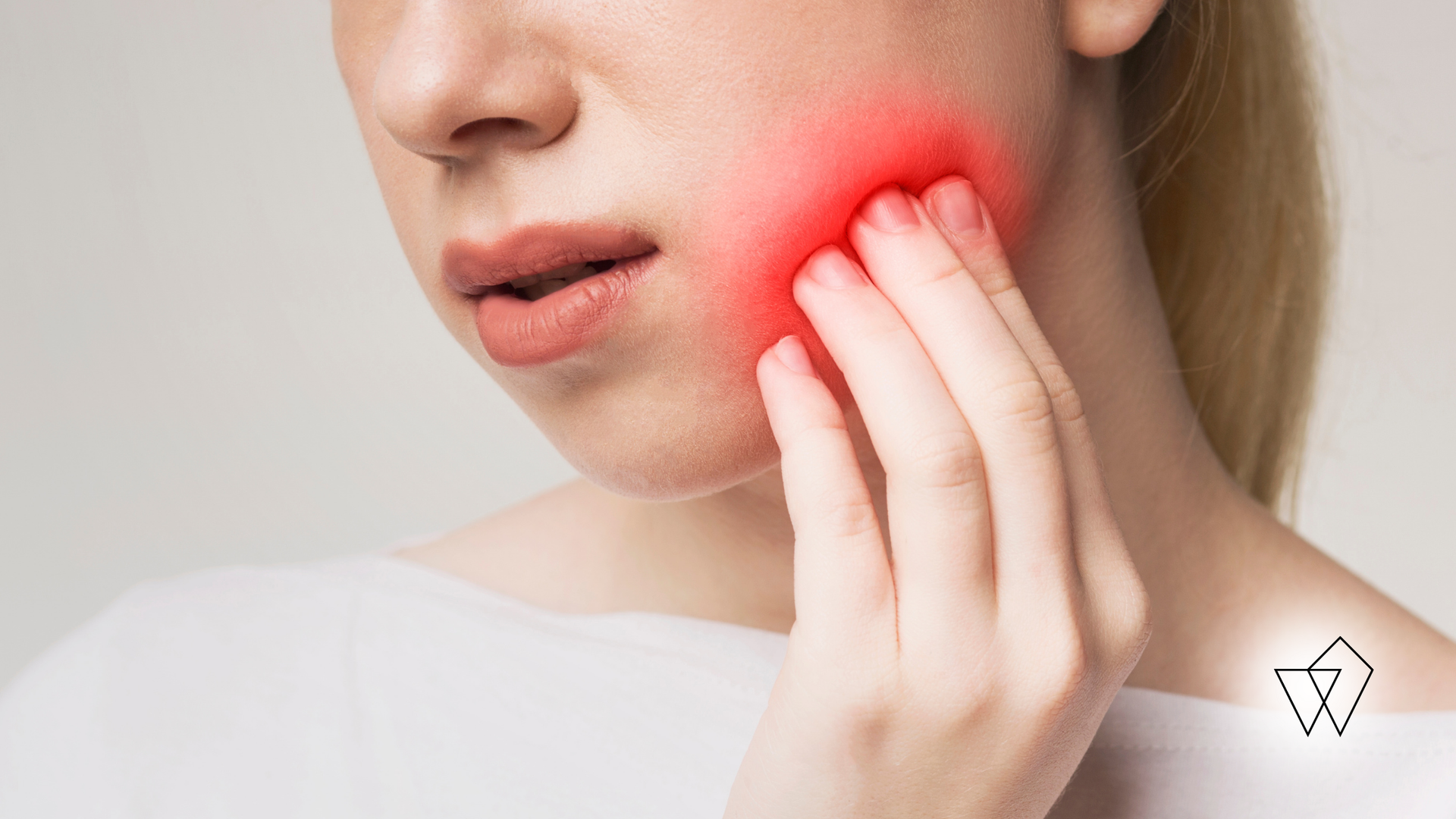 Person holding a red, painful jaw while touching their cheek, suggesting toothache or facial pain.