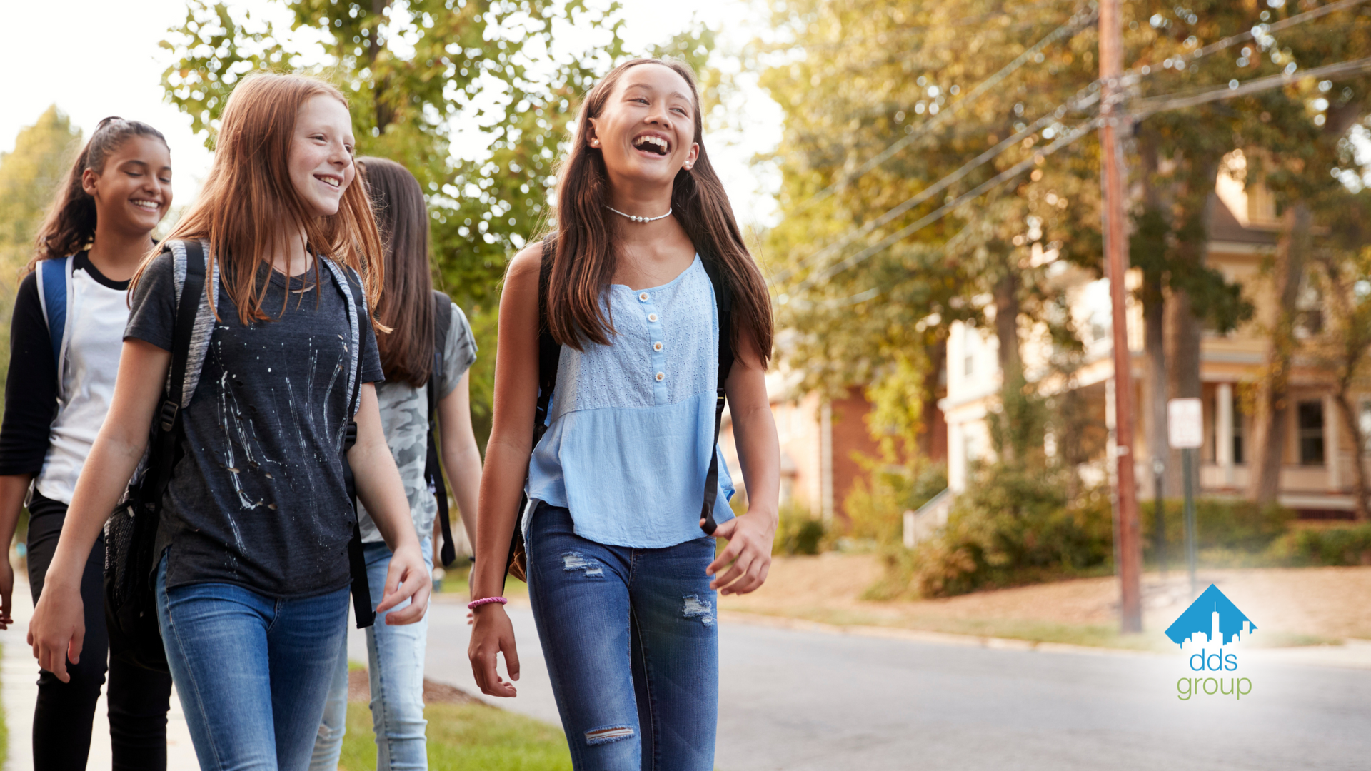 A group of young girls are walking down a sidewalk holding hands.