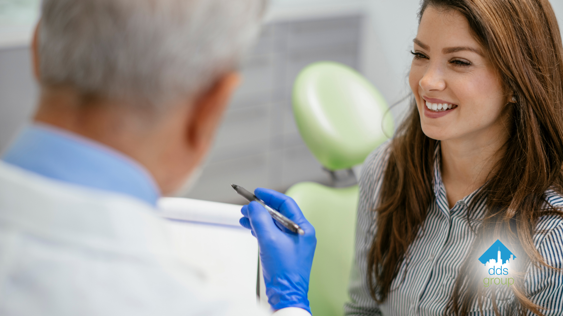 A woman is sitting in a dental chair talking to a dentist.