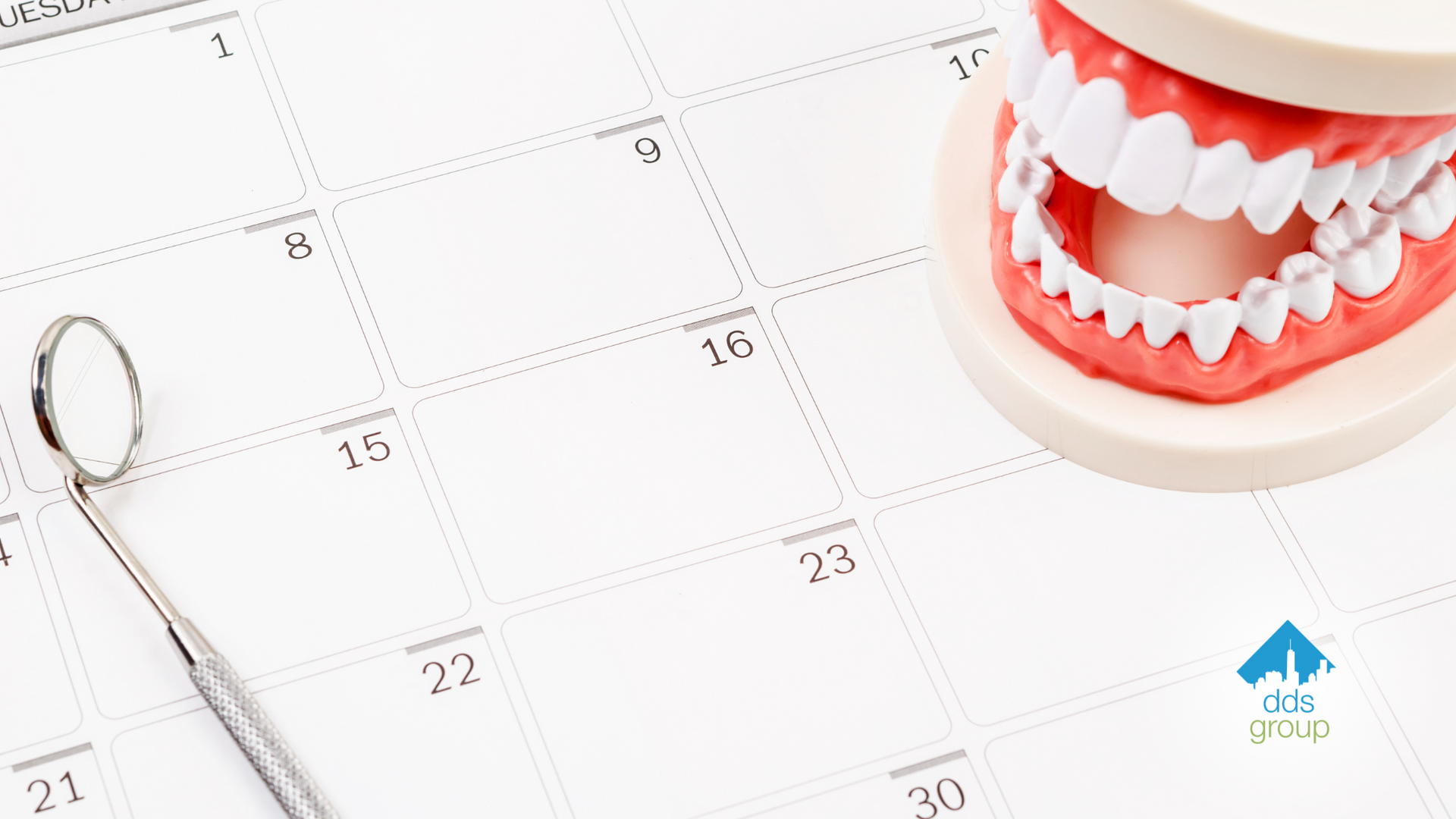 A calendar with a dental mirror and a model of teeth on it.