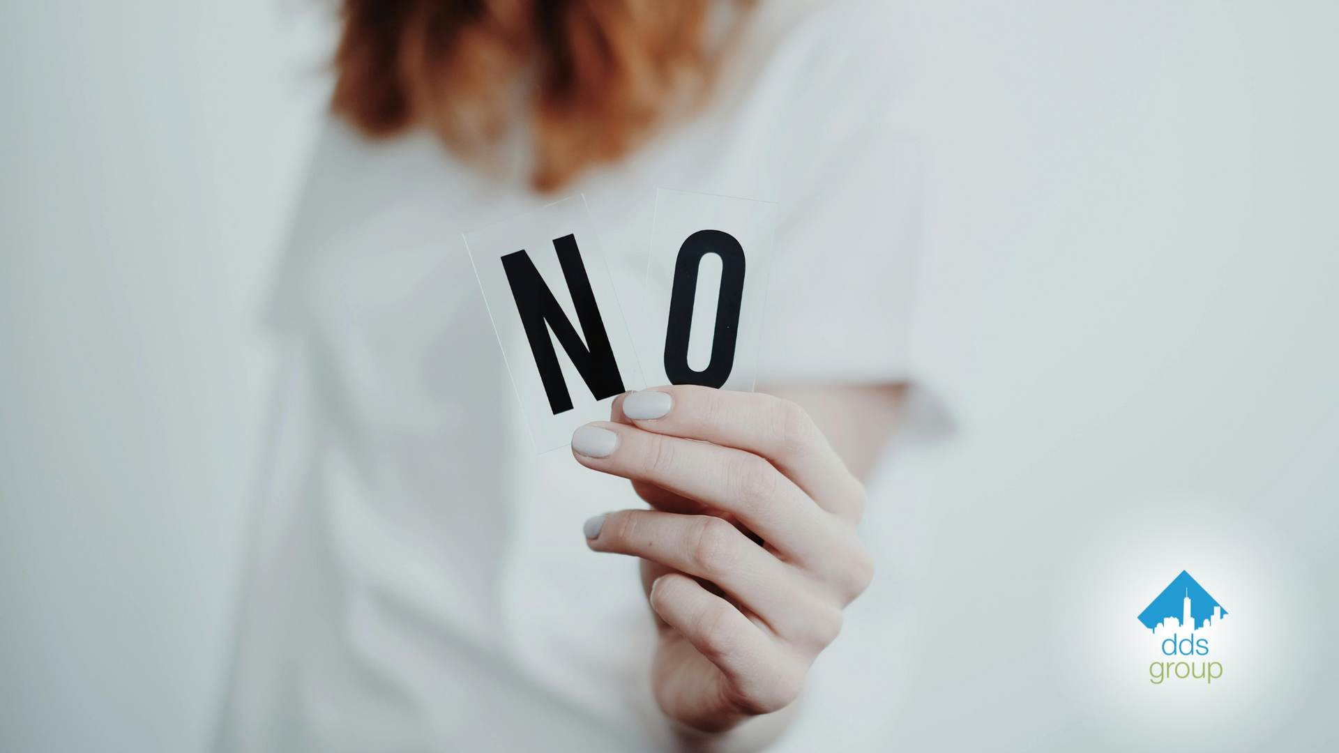 A woman is holding a piece of paper that says no.