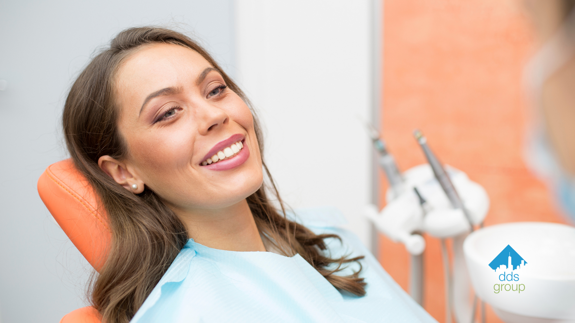 A woman is smiling while sitting in a dental chair.